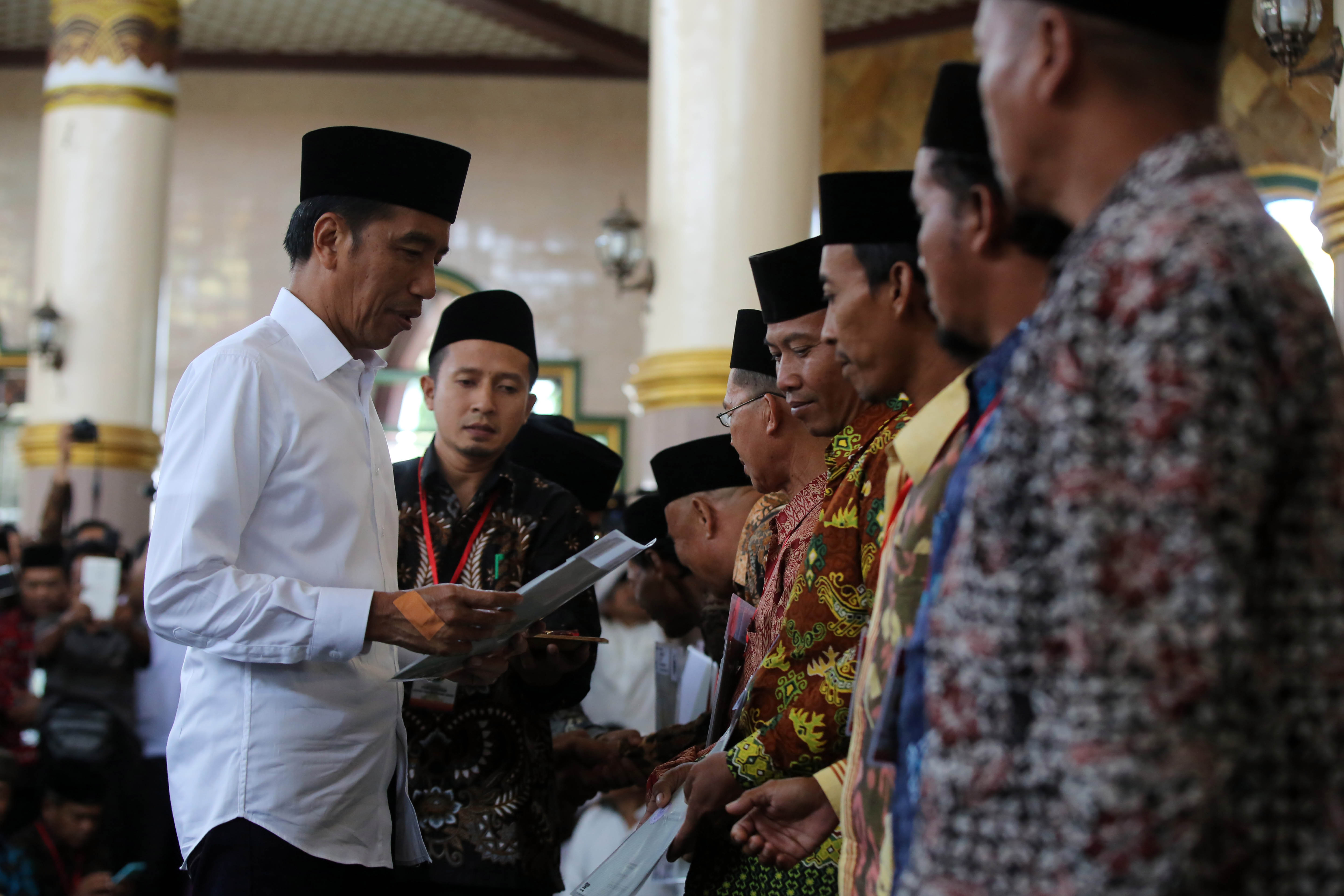 Presiden Joko Widodo menyerahkan sertifikat tanah wakaf usai melaksanakan ibadah Salat Jumat di Masjid Istiqlal, Lampung, Jumat (8/3/2019). 