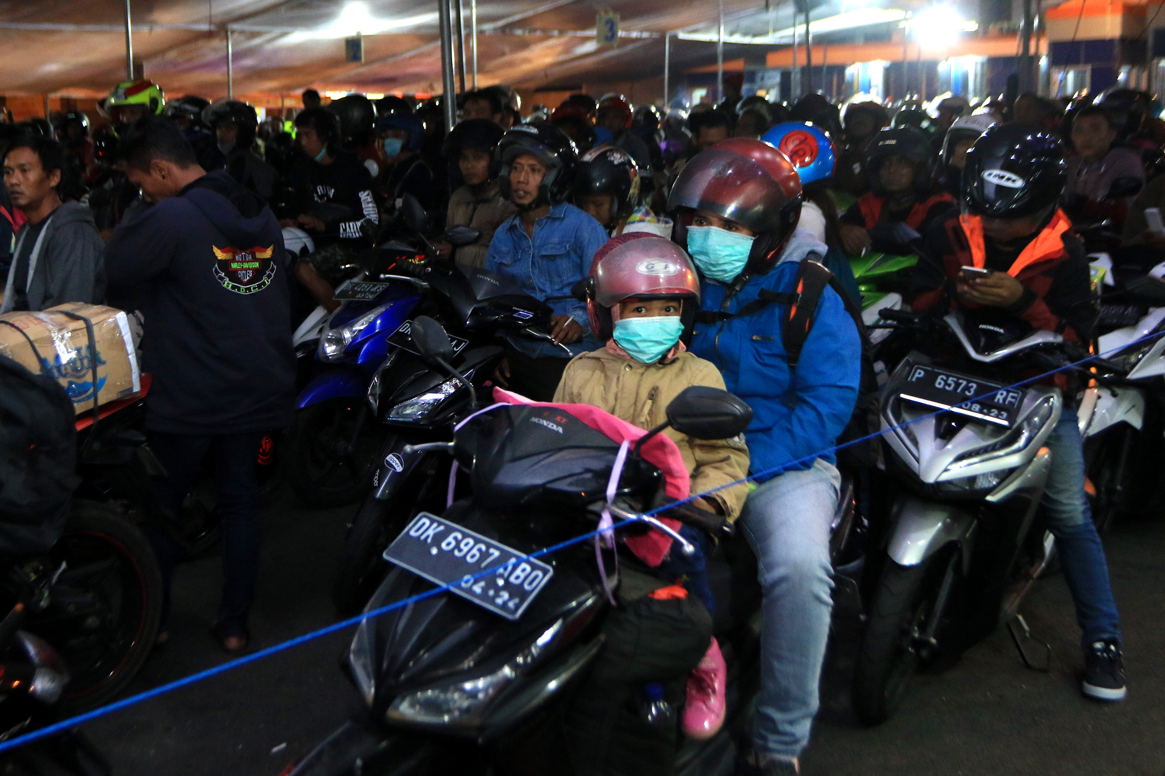 Pemudik menggunakan roda dua mengantre ditenda yang disediakan di lapangan parkir Pelabuhan Gilimanuk, Jembrana, Bali.