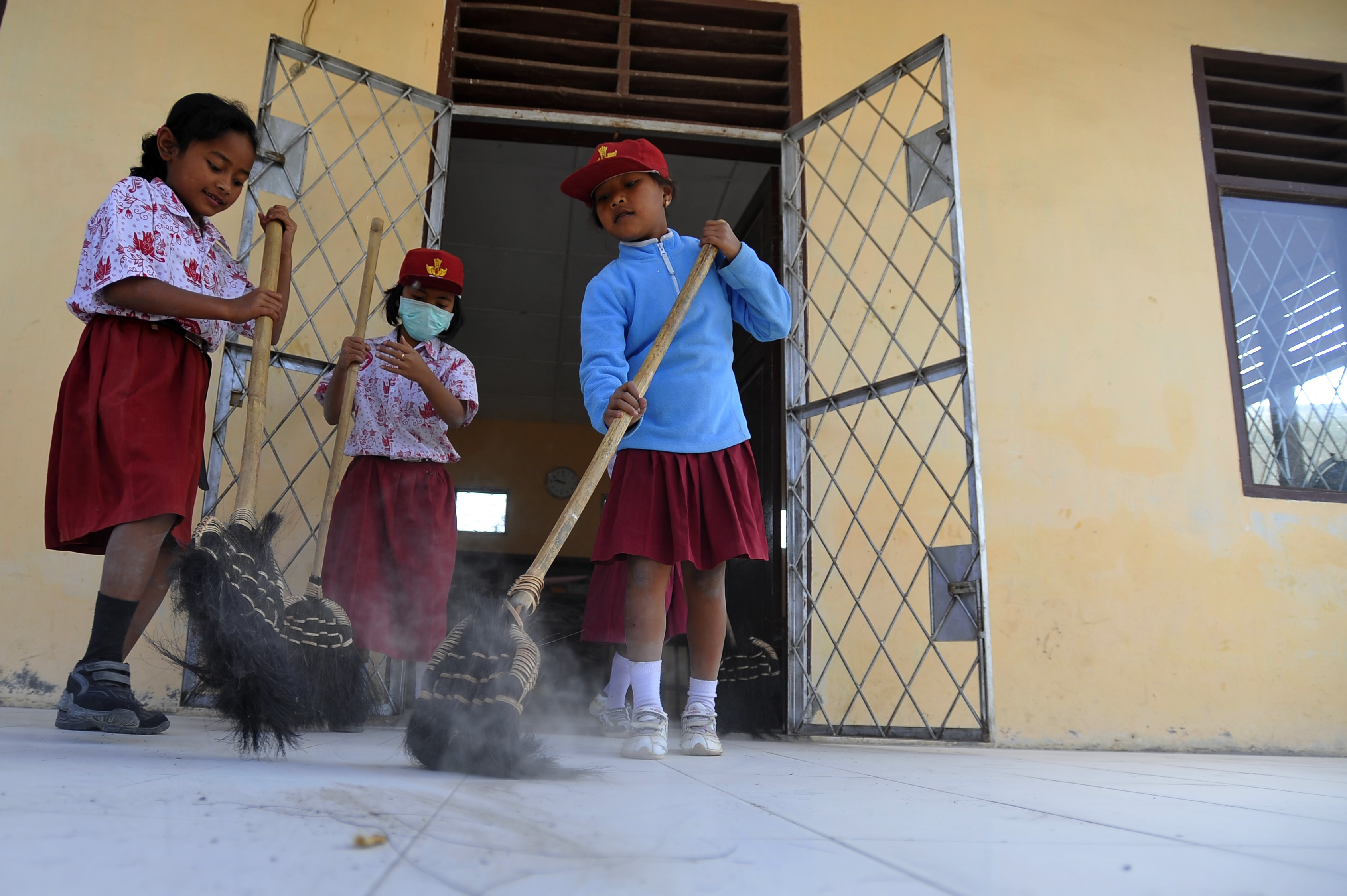  Tiga siswa membersihkan abu vulkanik erupsi Gunung Sinabung 