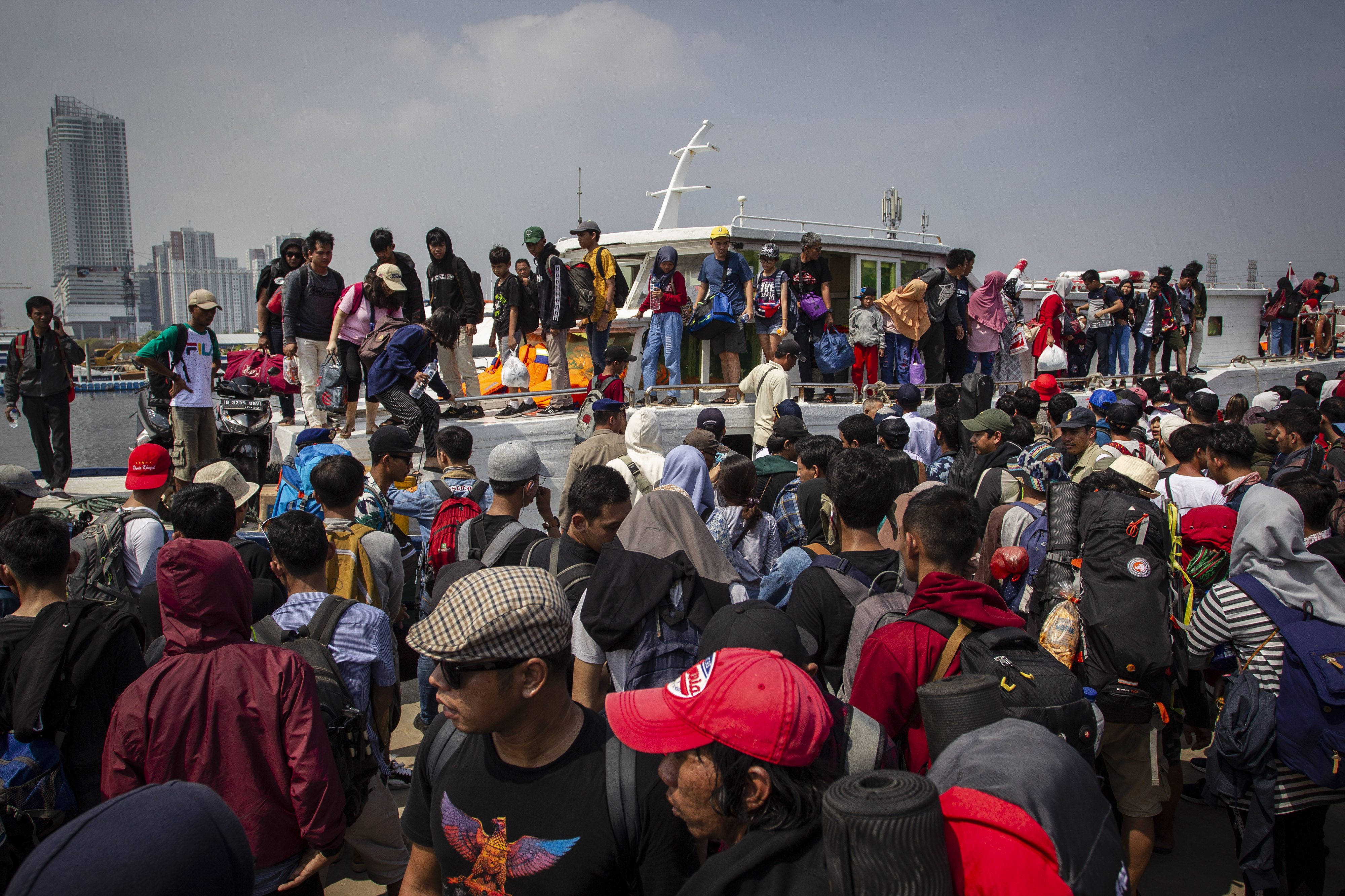 Wisatawan tujuan Kepulauan Seribu berusaha masuk ke dalam kapal di dermaga Kali Adem, Muara Angke, Jakarta, Sabtu (8/6).