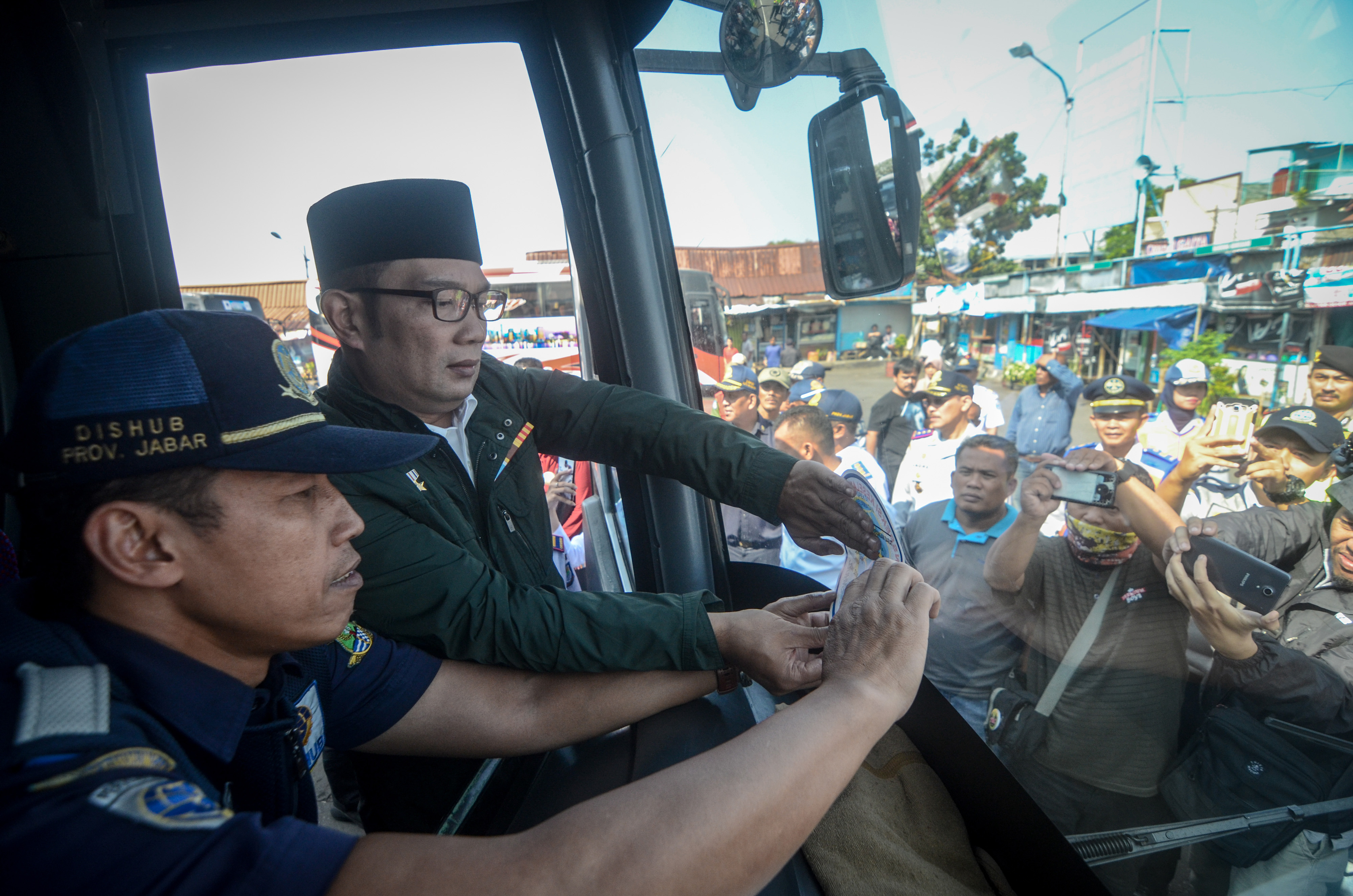  Gubernur Jawa Barat Ridwan Kamil memasang stiker tanda layak jalan saat meninjau arus mudik di Terminal Cicaheum, Bandung,