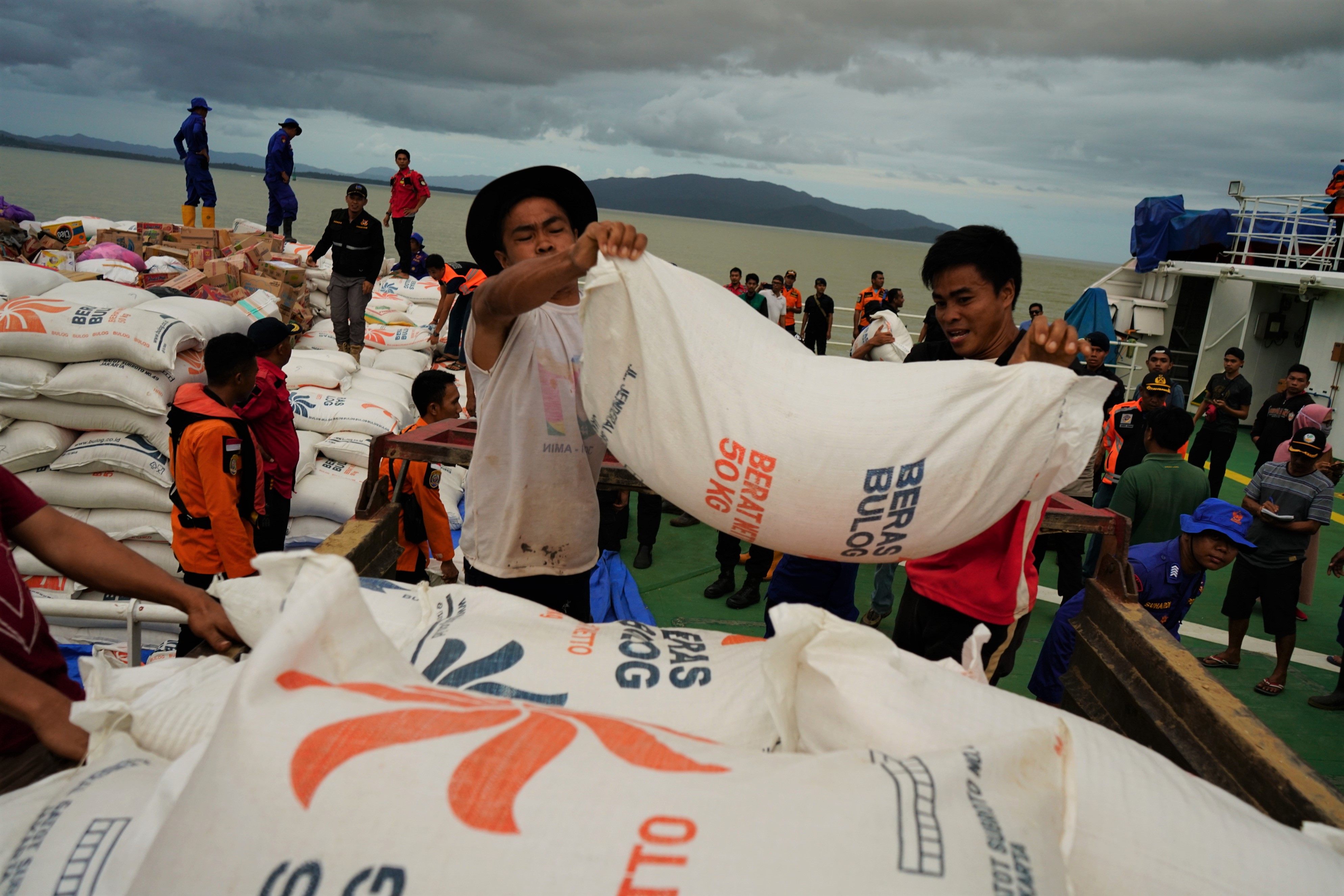 Personel TNI, Basarnas, Polri dan relawan menurunkan logisitik bantuan dari KN Pacitan di Dermaga Molawe, Konawe Utara