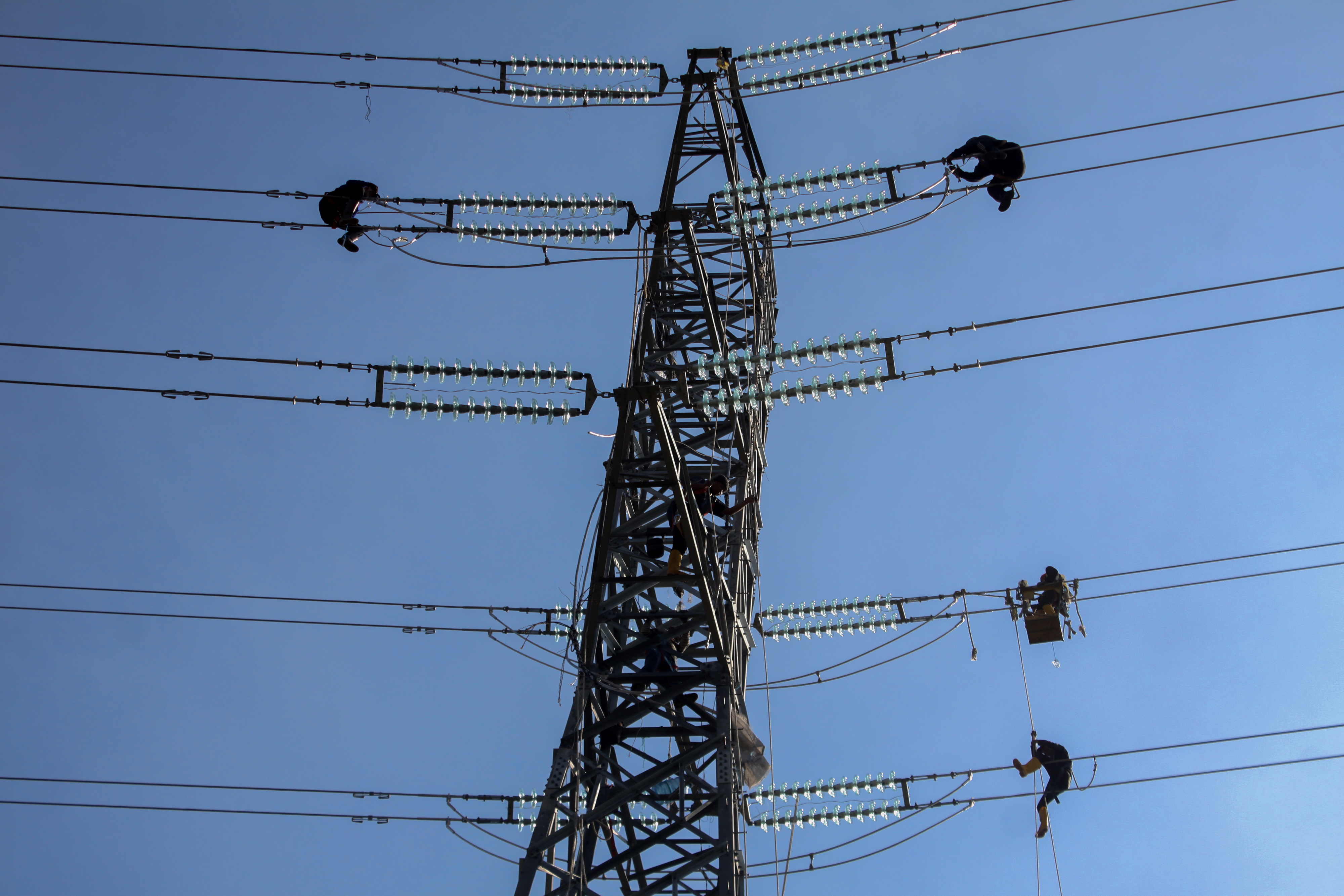 Pekerja memasang instalasi listrik di menara Saluran Udara Tegangan Ekstra Tinggi (SUTET) 