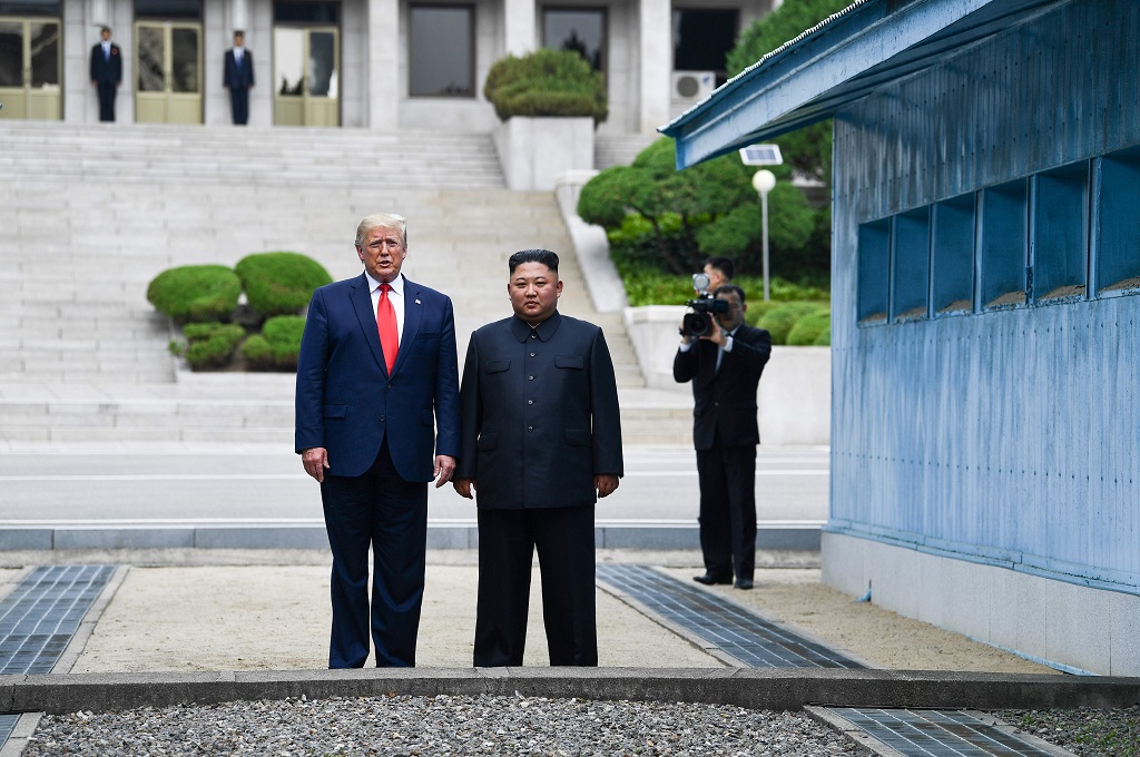 Presiden AS Donald Trump (kiri) dan pemimpin Korut Kim Jong-un berpose untuk awak media di DMZ, Minggu 30 Juni 2019. 
