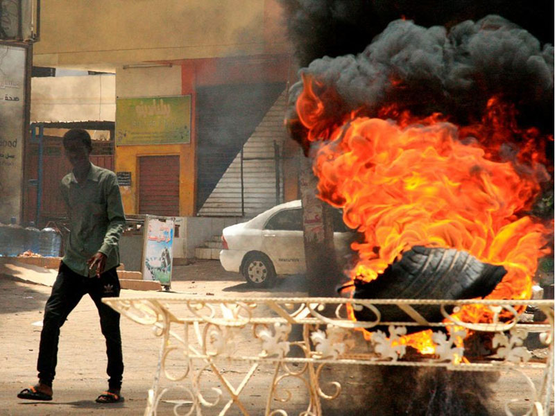 Para pendemo membakar ban sebagai tanda protes terhadap militer.