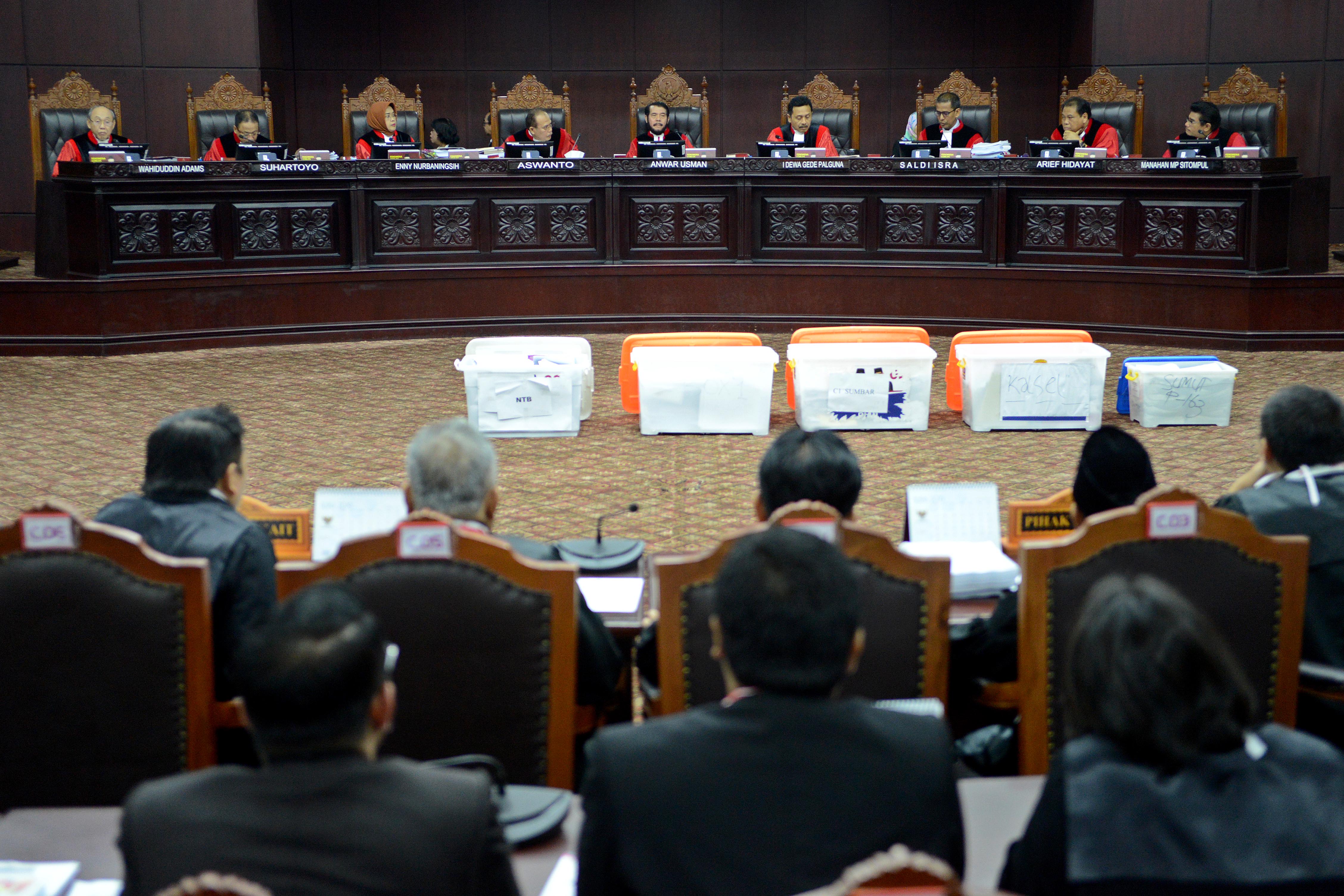 Hakim Konstitusi yang dipimpin Anwar Usman (tengah) menunjukkan empat kontainer alat bukti dari pihak Pemohon