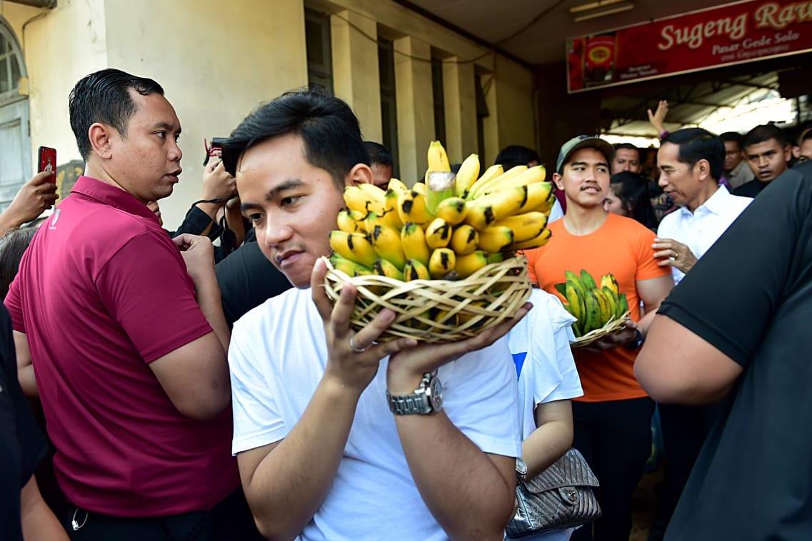Presiden Jokowi dan kedua putranya, Gibran Rakabuming Raka dan Kaesang Pangarep, membawa pisang hasil belanjaan.