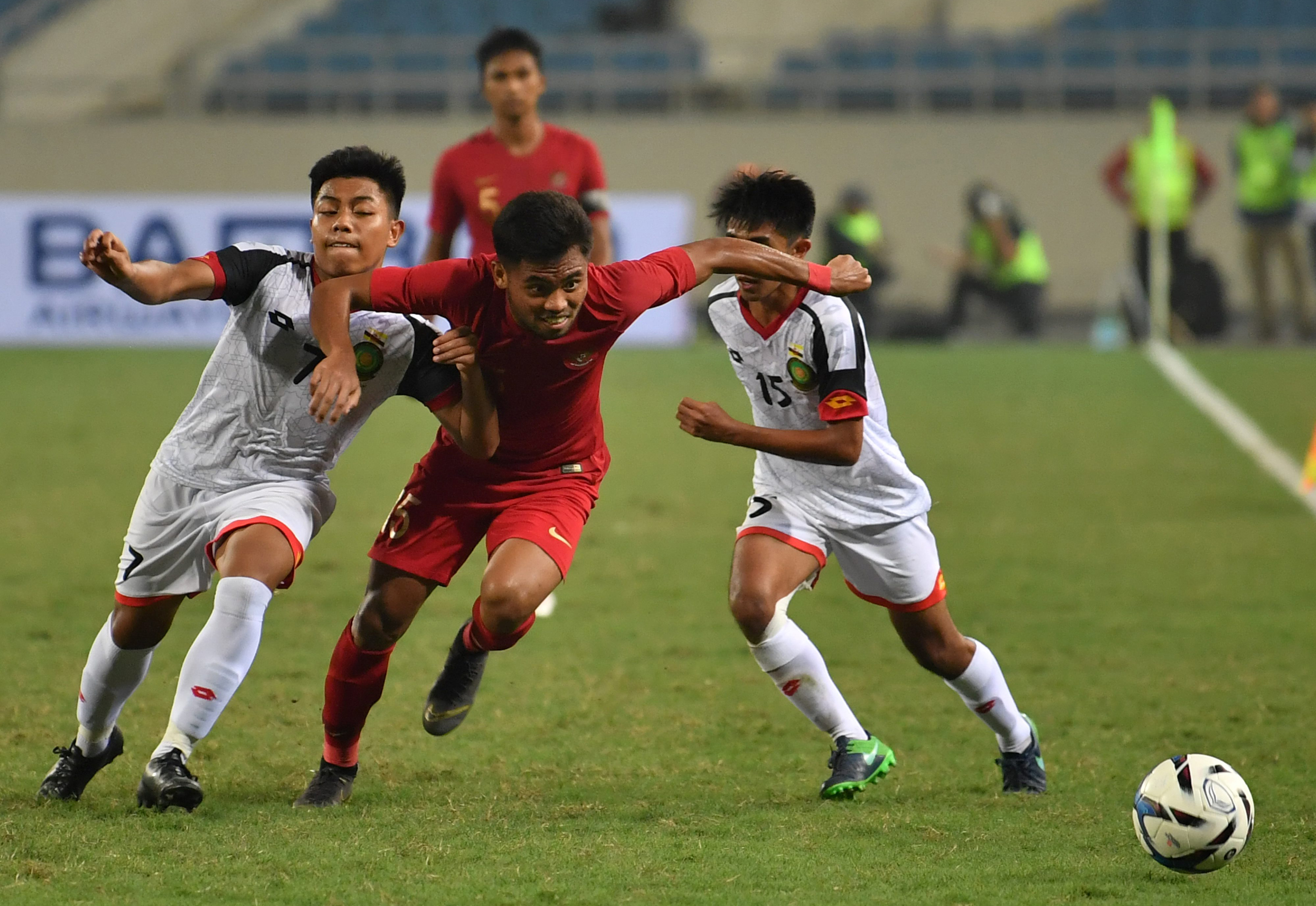 Pesepak bola tim nasional Indonesia U-23 Saddil Ramdani (tengah) berupaya meloloskan diri dari kawalan dua pesepak bola timnas Brunei