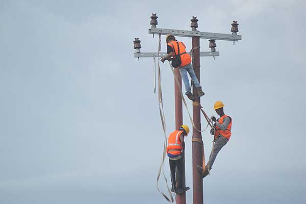 Pekerja memasang jaringan di tiang listrik baru 