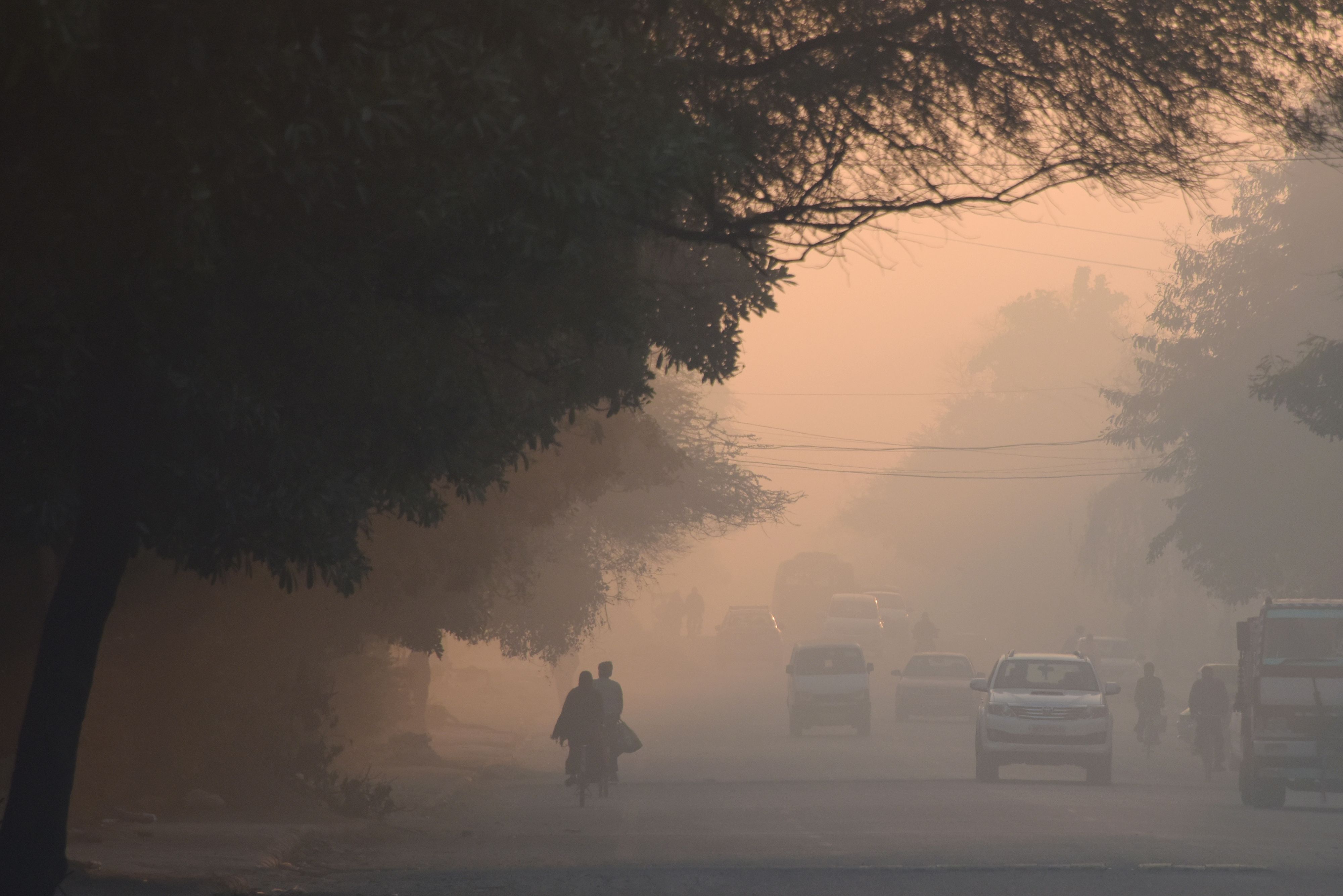 Orang-orang India berjalan di tengah kabut tebal di Gurgaon pada 7 Maret 2019.