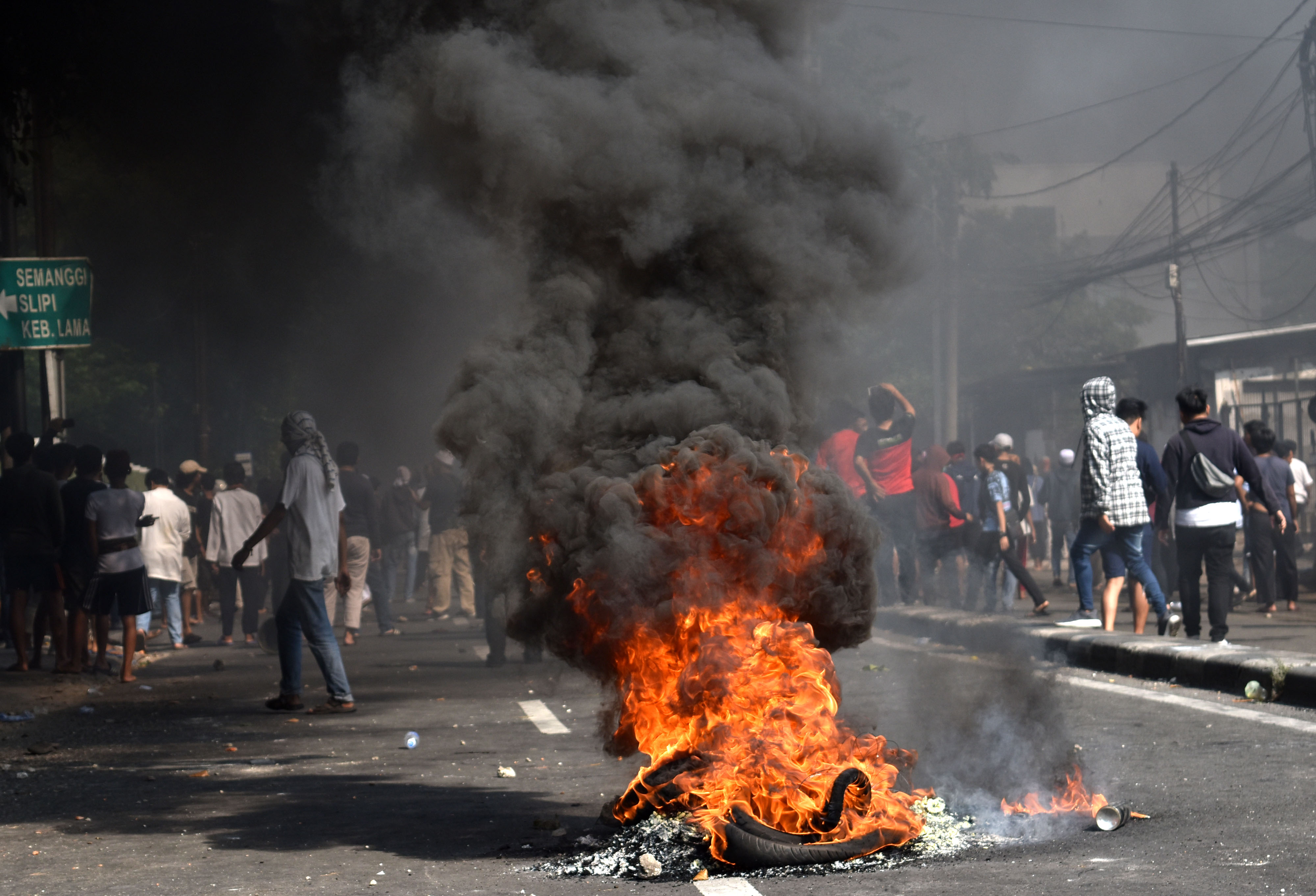 Sejumlah warga melintasi ban yang dibakar di tengah Jalan KS. Tubun, Petamburan, Jakarta Pusat, Rabu (22/5/2019)