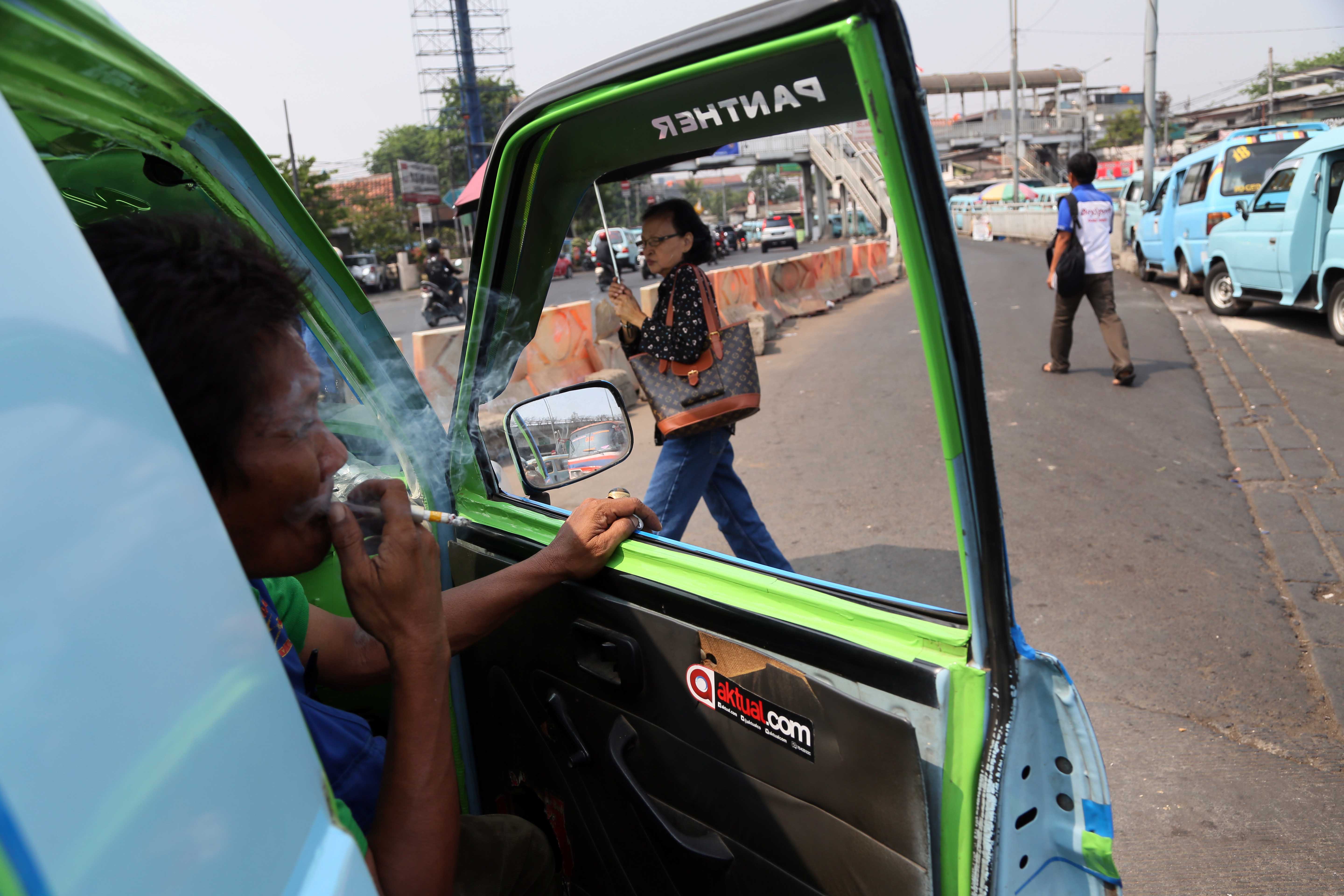 Ilustrasi: Supir merokok di dalam angkot saat menunggu penumpang Terminal Kampung Melayu, Jakarta, beberapa waktu lalu.