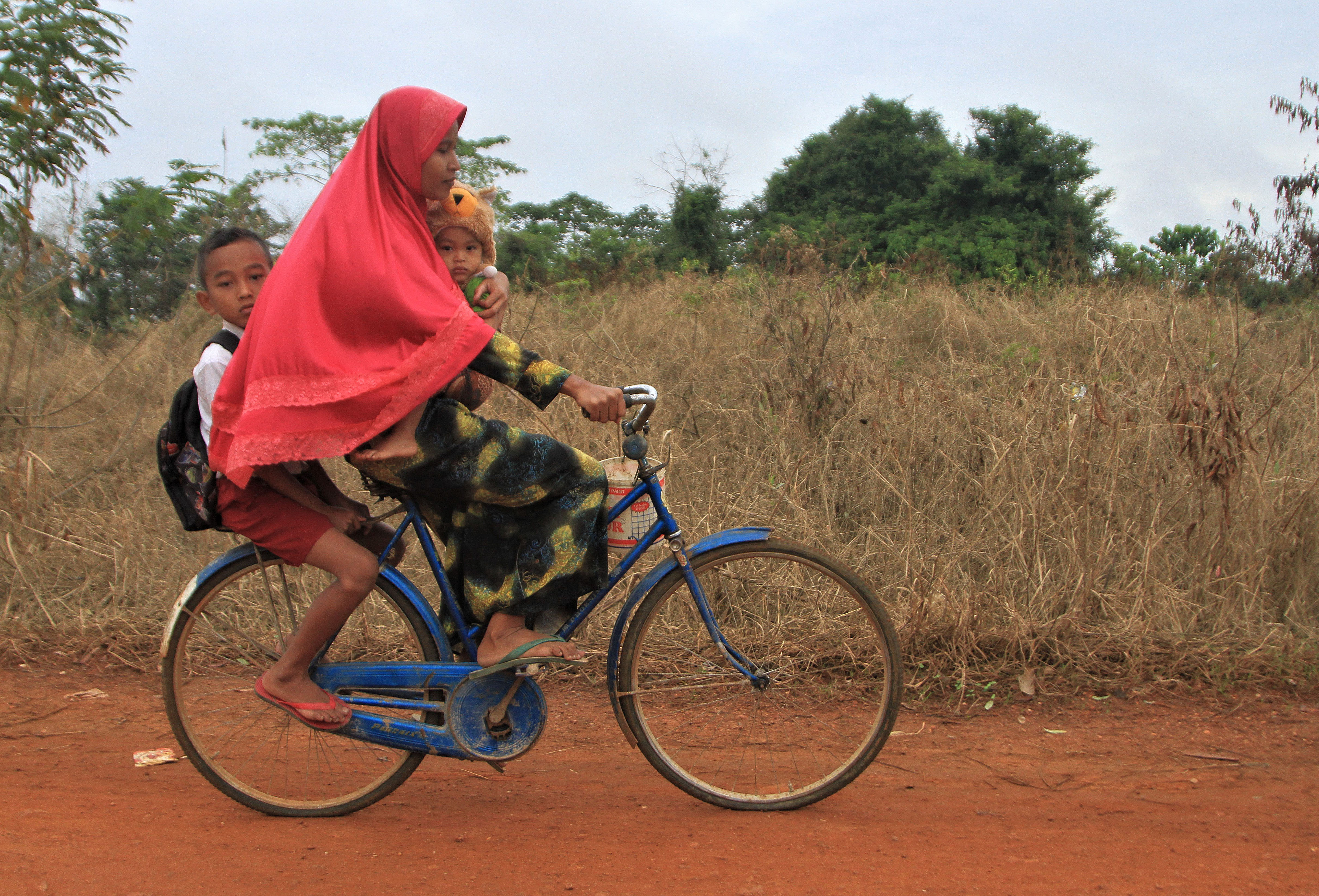Ibu mengendarai sepeda bersama dua anaknya. 