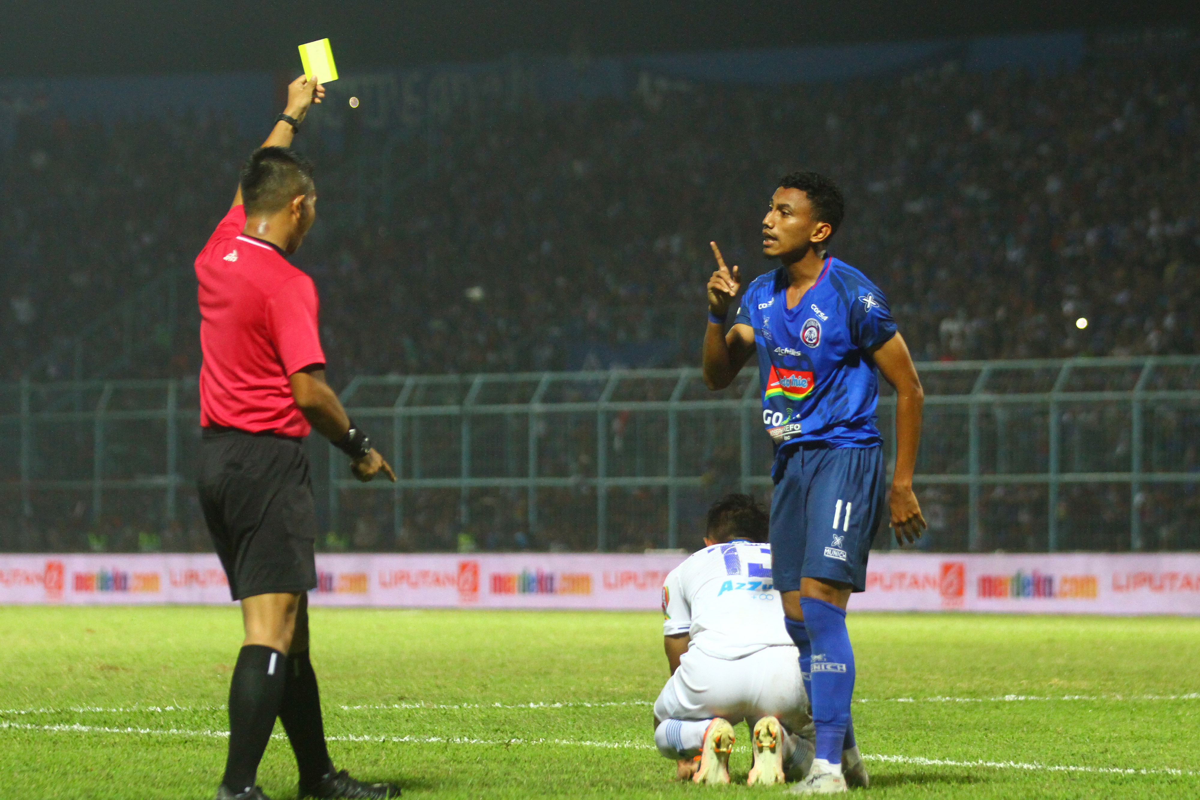 Pemain Arema FC Rivaldi Bawuo (kanan)  diberi kartu kuning akibat melakukan pelanggaran pada pemain Persib,  Febri Hariadi (tengah).