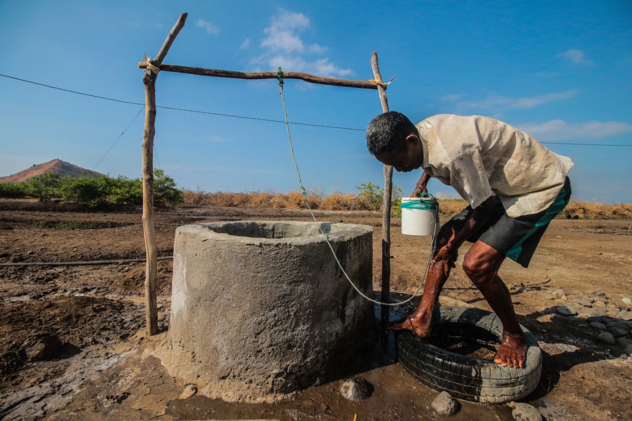 Warga Dusun 01 Desa Waekokak Markus Madhi menimba air sumur untuk yang hanya digunakan untuk mencuci kaki karena sangat asin.