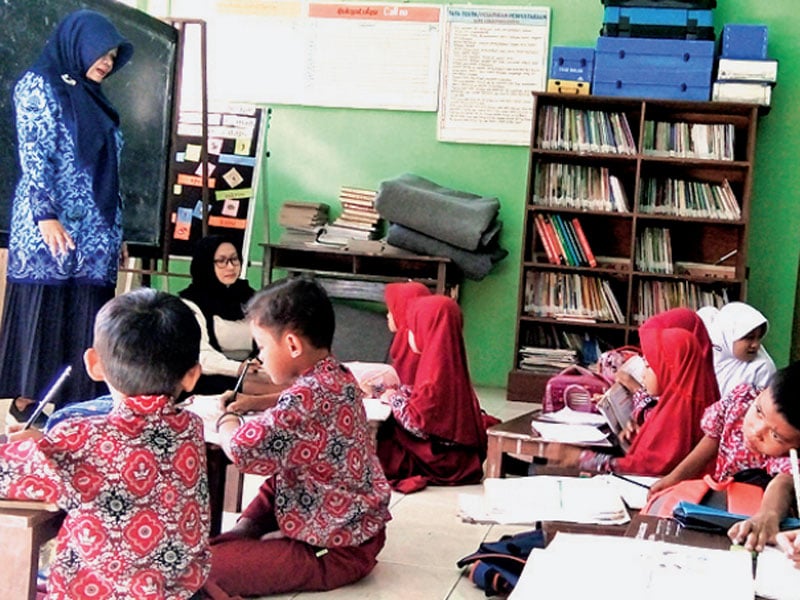Siswa kelas dua Sekolah Dasar Negeri (SDN) Cikadongdong mengikuti Kegiatan Belajar Mengajar (KBM) di lantai ruang perpustakaan.