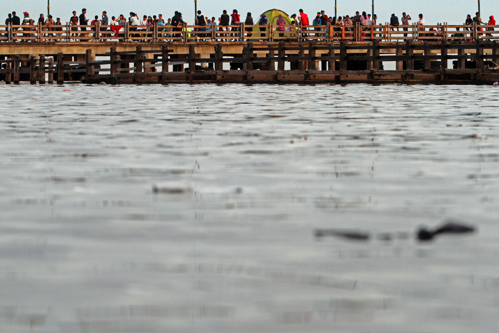  Warga menikmati pemandangan laut di kawasan Ancol, Jakarta Utara, Selasa (1/1). 