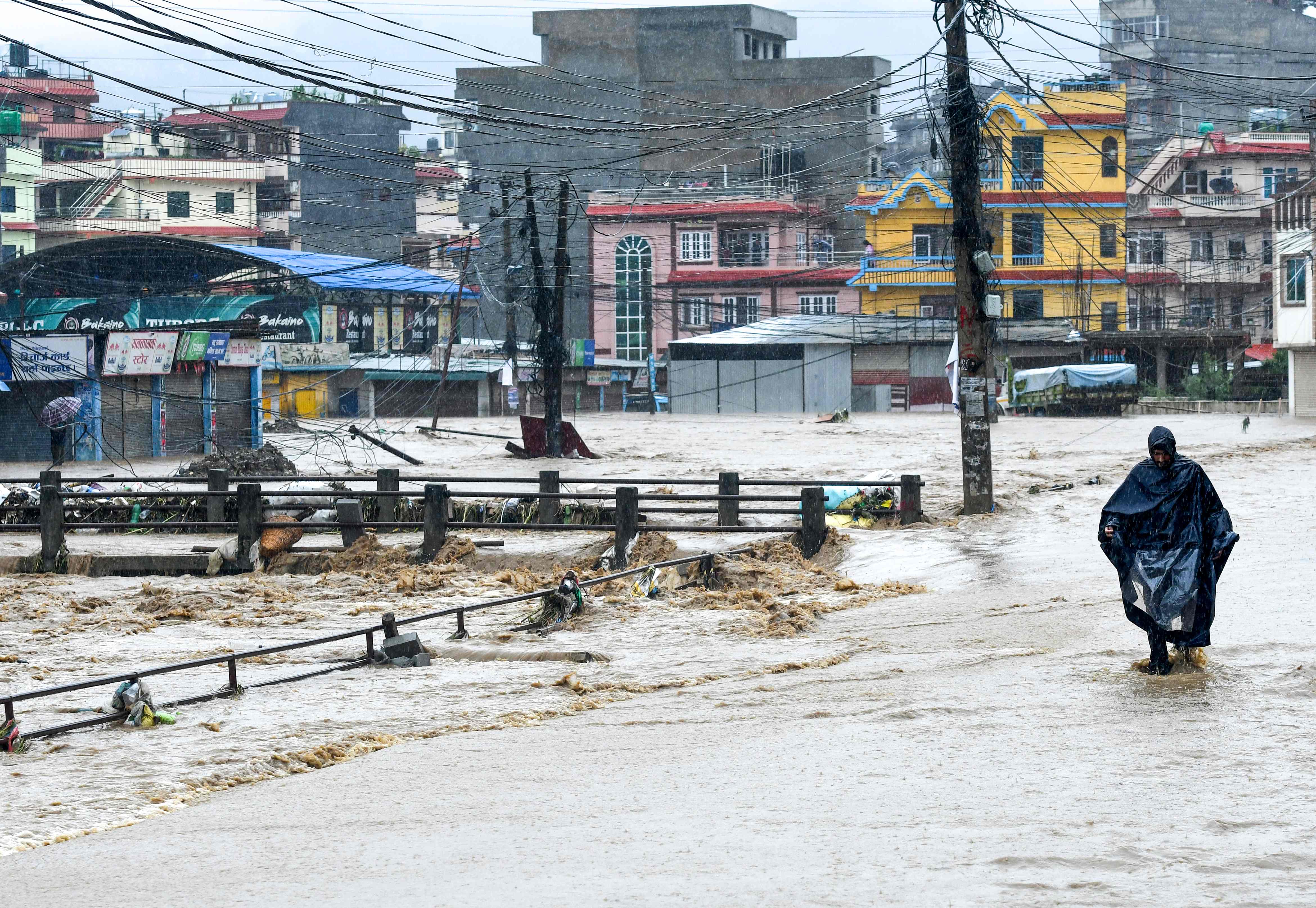 Seorang warga Nepal berjalan melalui genangan air setelah Sungai Balkhu meluap menyusul hujan musim di daerah Kalanki di Kathmandu