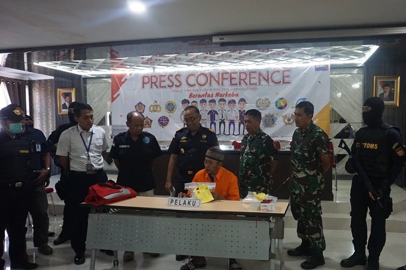 Tersangka penyelundup sabu seberat 815 gram dalam lipatan baju sedang diperiksa.