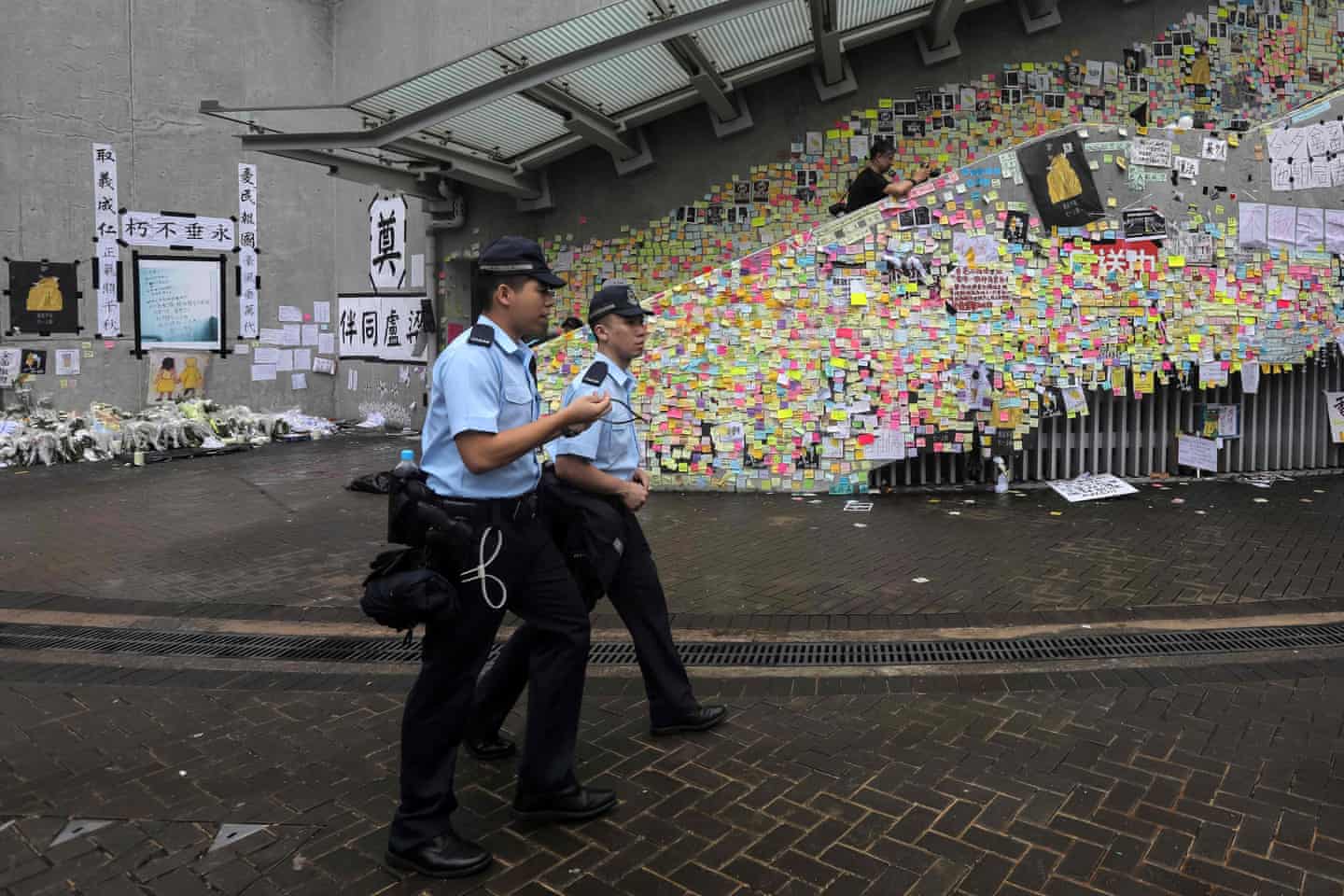 Dua polisi Hong Kong berjalan melintasi 'Tembok Lennon' di Kota Hong Kong.