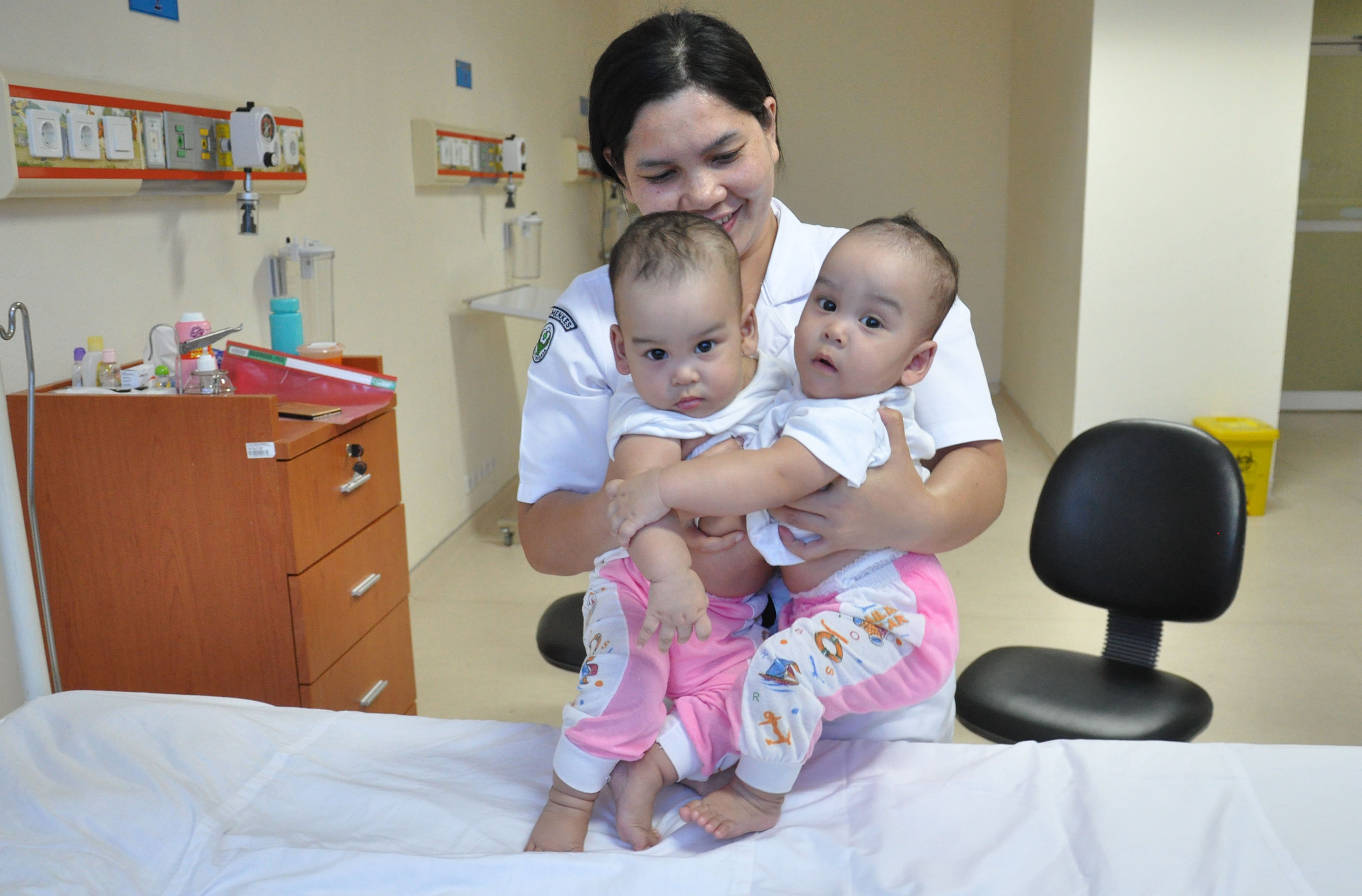 Perawat menggendong bayi kembar siam Adam dan Malik