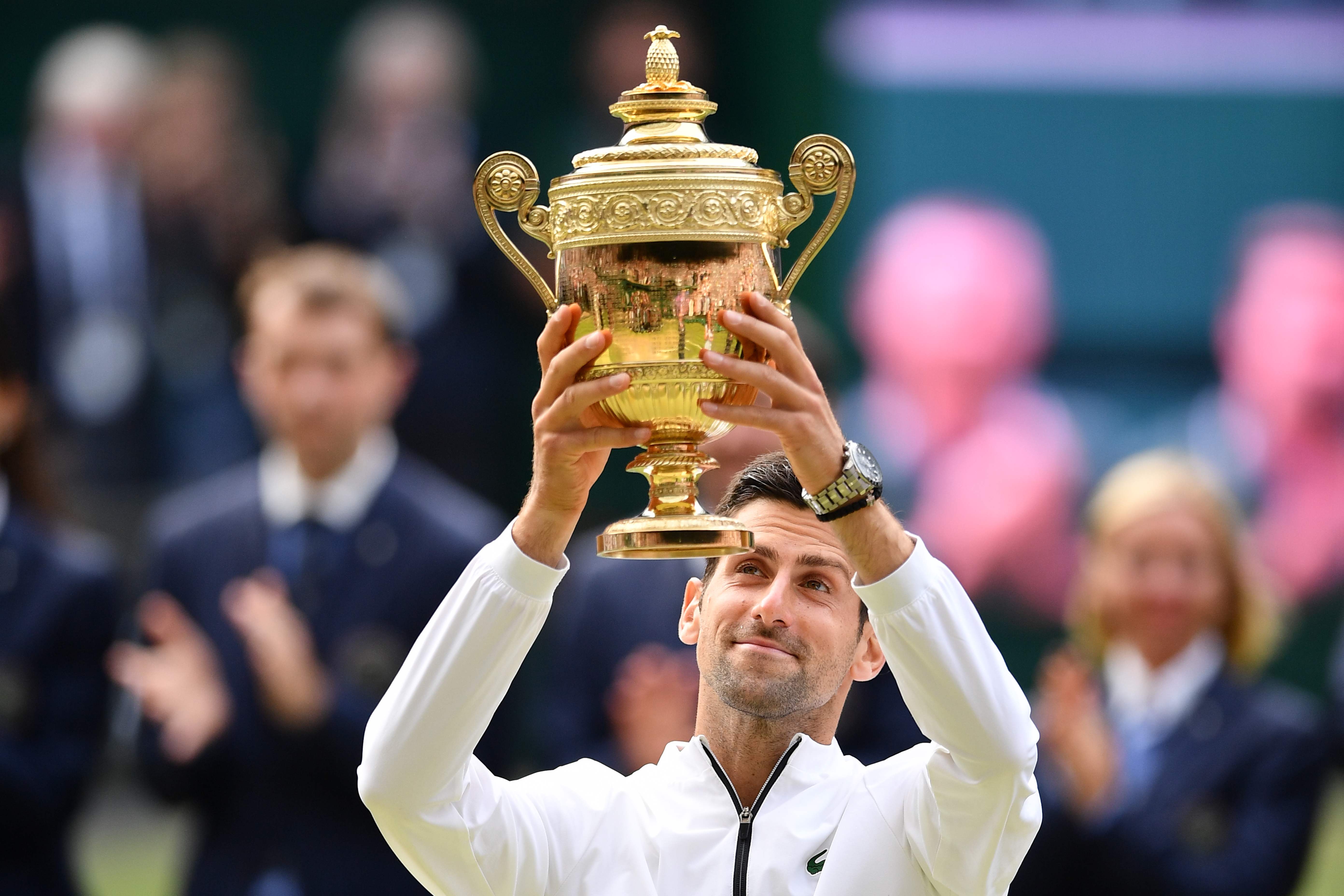 Petenis Serbia Novak Djokovic mengangkat trofi Wimbledon seusai mengalahkan petenis Swiss Roger Federer.