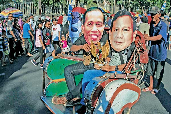 Warga memakai topeng Joko Widodo dan Prabowo Subianto, saat aksi Hari Bebas Kendaraan Bermotor (HBKB) di Surakarta, Jawa Tengah, kemarin.