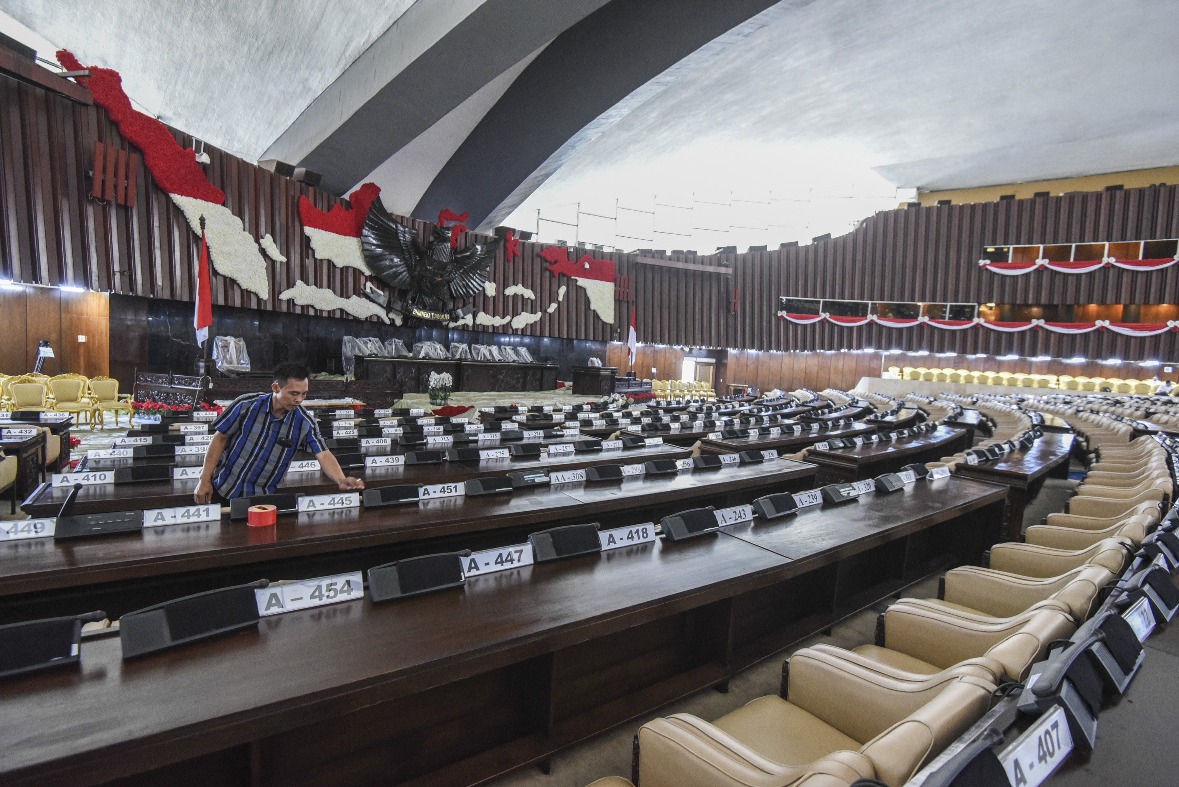 Seorang pekerja tengah menata papan nama di ruang rapat paripurna Gedung Nusantara, Kompleks Parlemen, Senayan, Jakarta, Selasa (14/8).