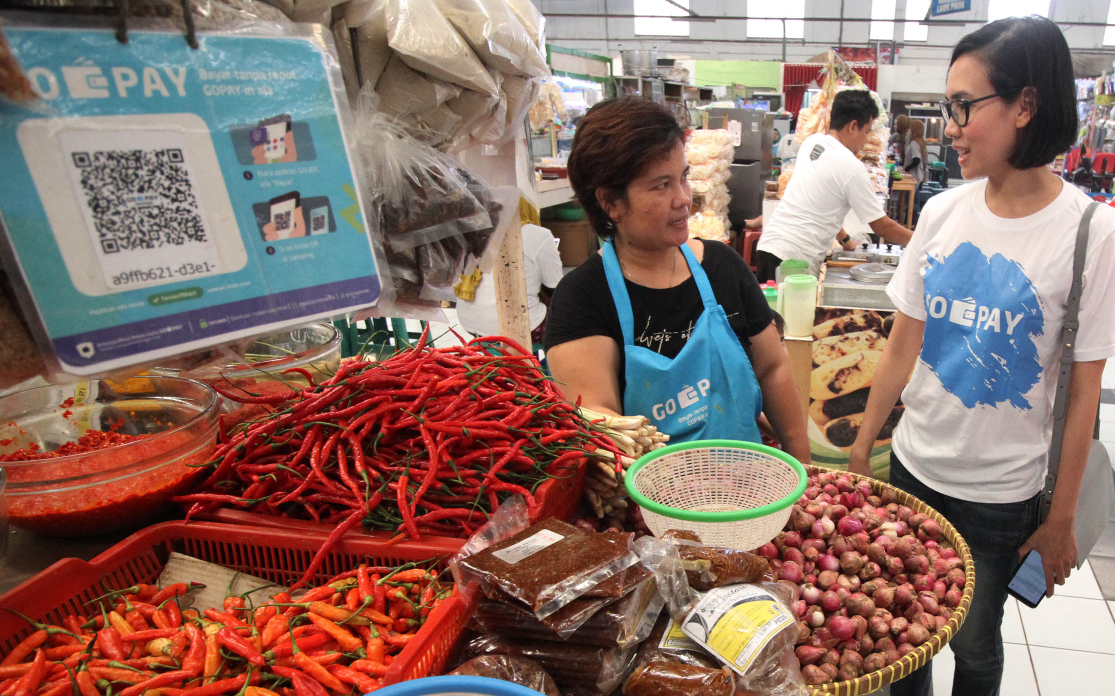 Pedagang sayur menggunakan aplikasi digital Gopay.