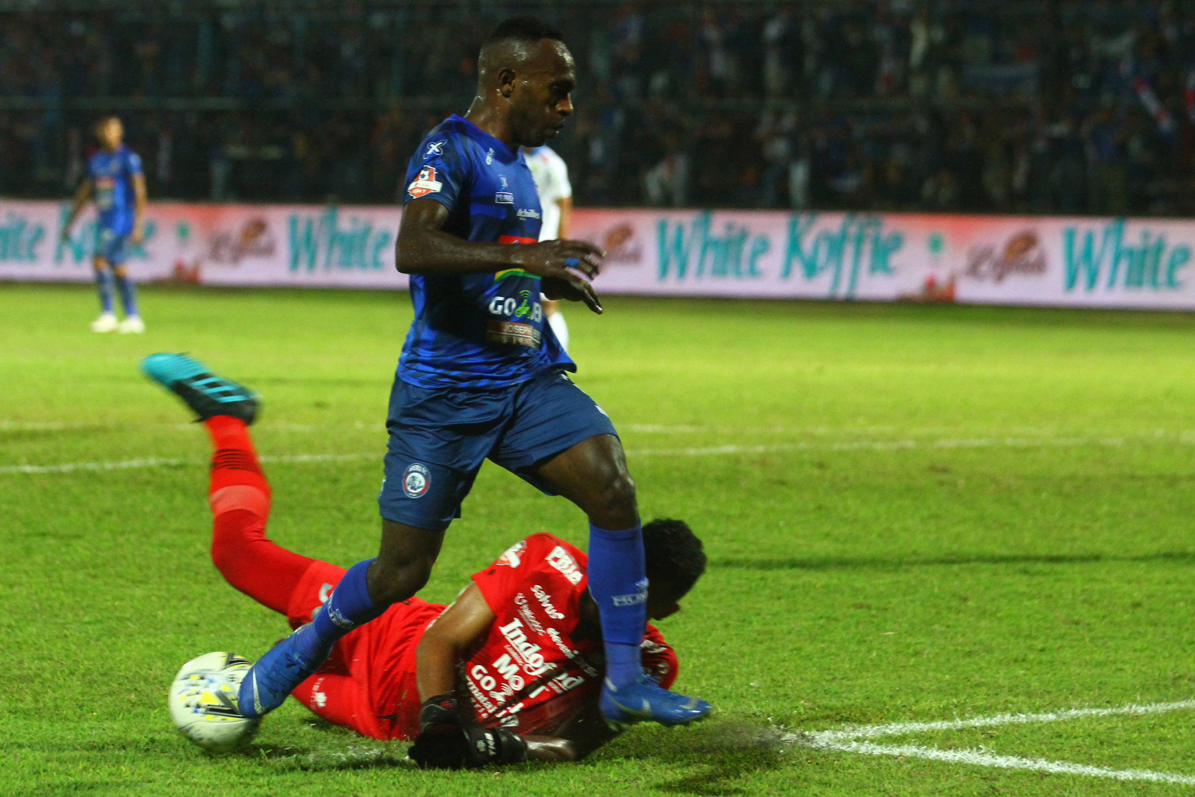 Kiper Persib Muhammad Agil Savik (bawah) berusaha menghalau bola dari kaki pemain Arema Riki Kayame (kiri) dalam pertandingan Liga I