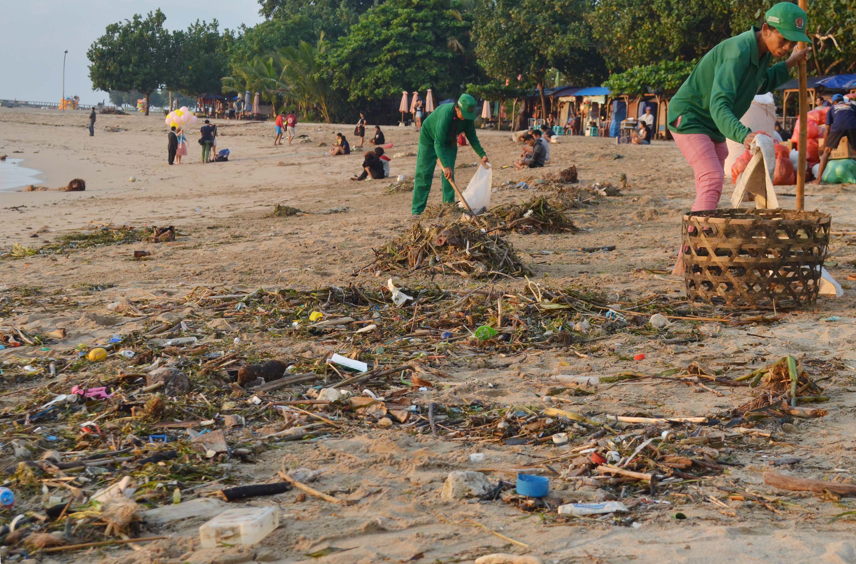  Pekerja membersihkan sampah yang berserakan di Pantai Sanur, Bali,