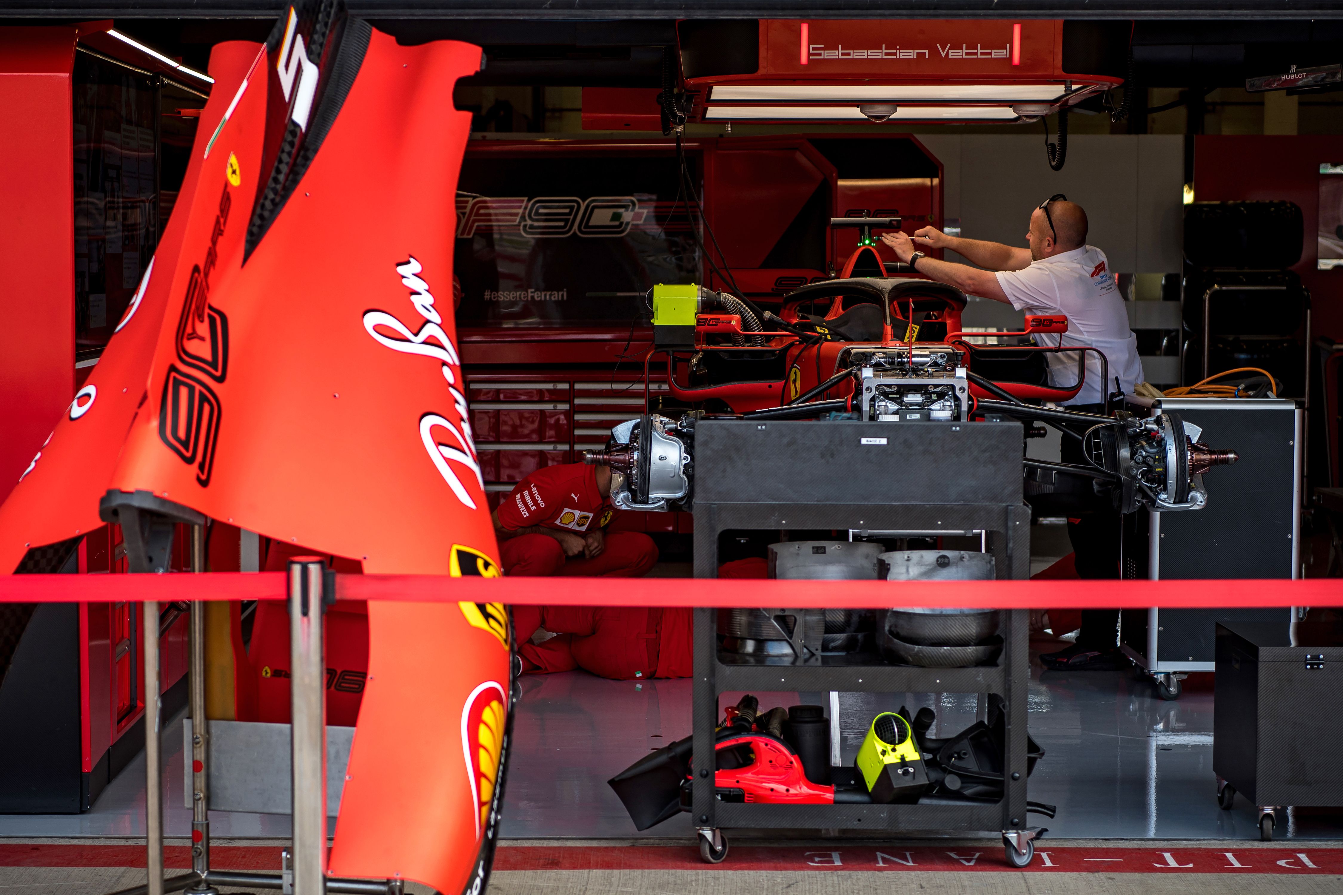 Seorang mekanik tengah bekerja di mobil Ferrari yang dikendarai Sebastian Vettel.