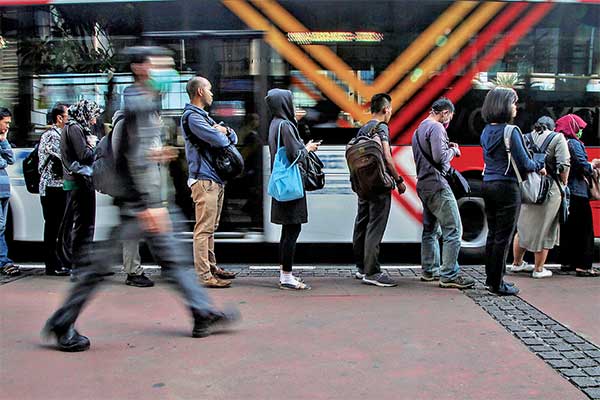 Para pekerja antre untuk menaiki bus Metro-Trans di Halte Sudirman, Jakarta, pekan lalu.