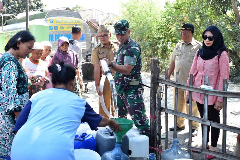 Dansatgas TMMD/Dandim Letkol Infanteri Richard Arnold Yeheskiel Sangari (memegang selang air) mendistribusikan air kepada warga.