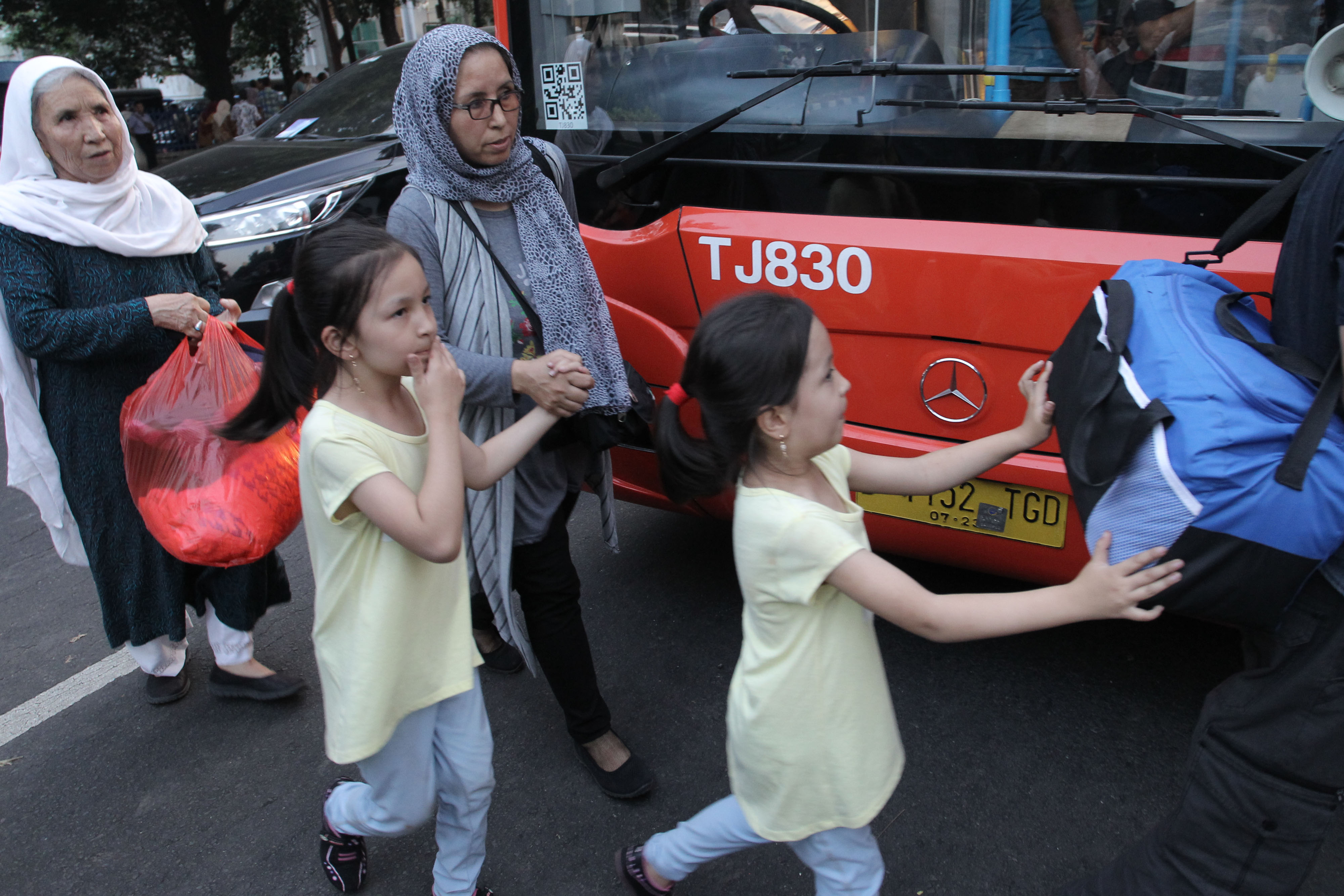 Sejumlah pencari suaka melintas untuk memasuki bus saat akan dipindahkan dari trotoar kawasan Kebon Sirih, Jakarta.