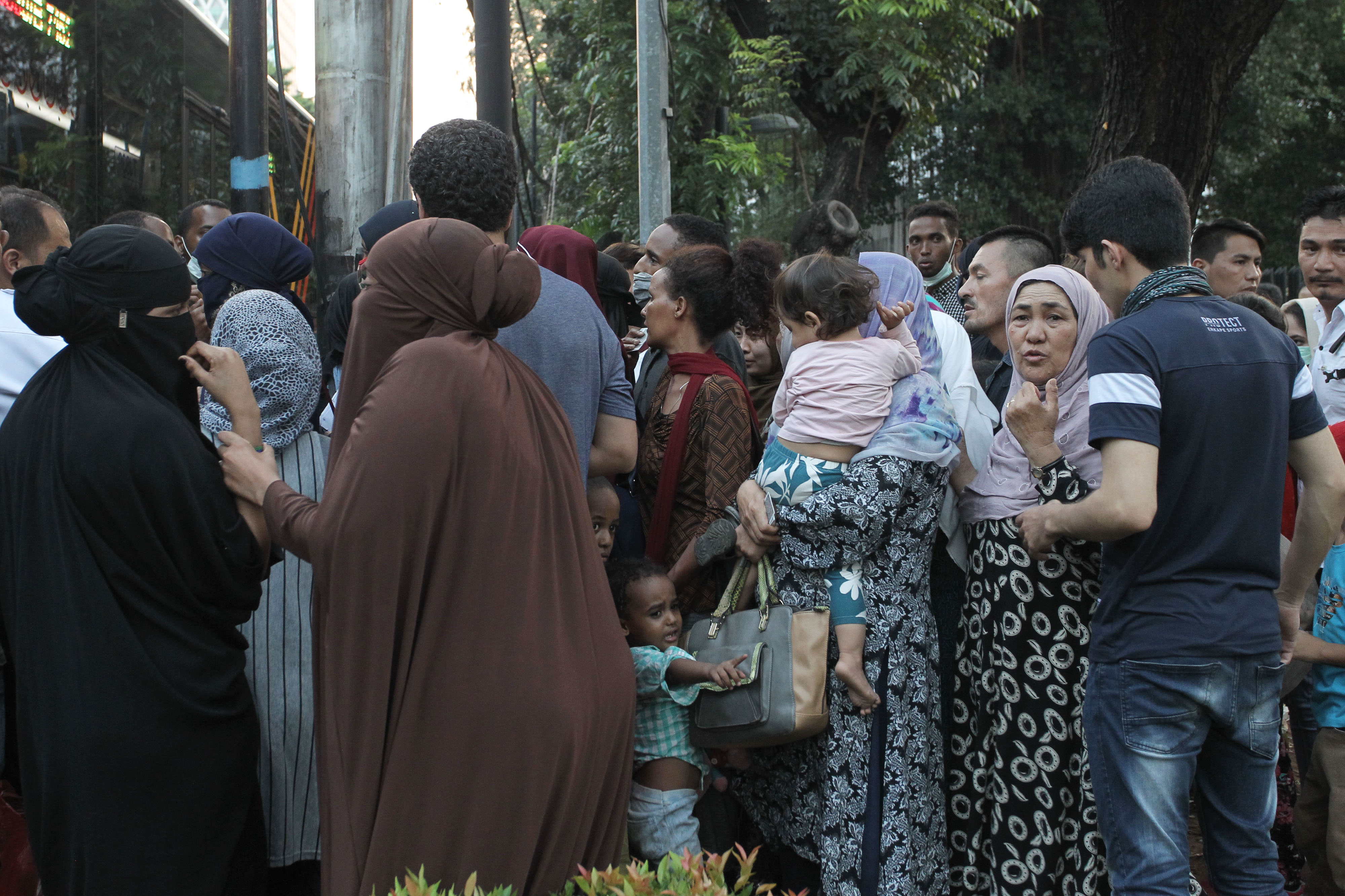 PEMINDAHAN PENCARI SUAKA: Sejumlah pencari suaka mengantre untuk memasuki bus saat akan dipindahkan dari trotoar kawasan Kebon Sirih 