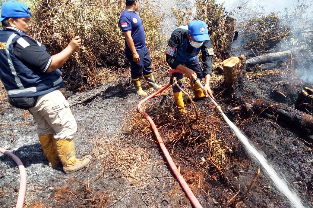 Petugas memadamkan kebakaran lahan milik masyarakat di Kota Palangkaraya.