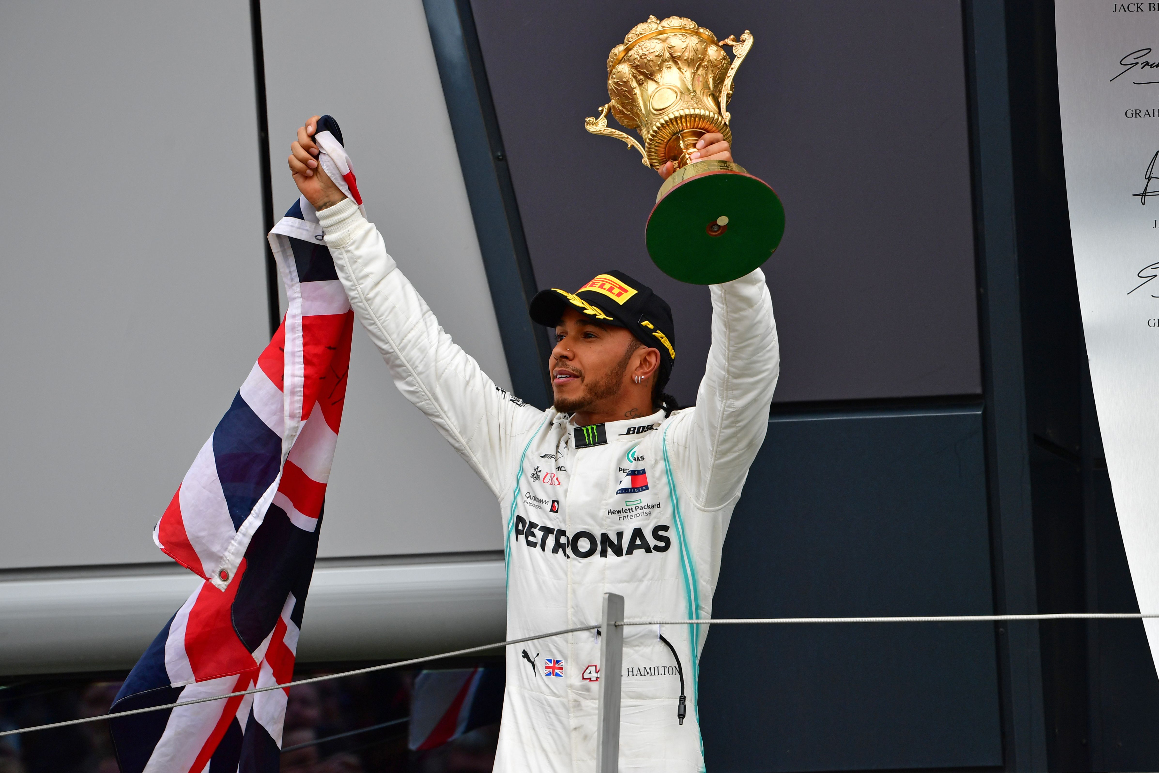 Pembalap Mercedes, Lewis Hamilton mengangkat trofi juara.