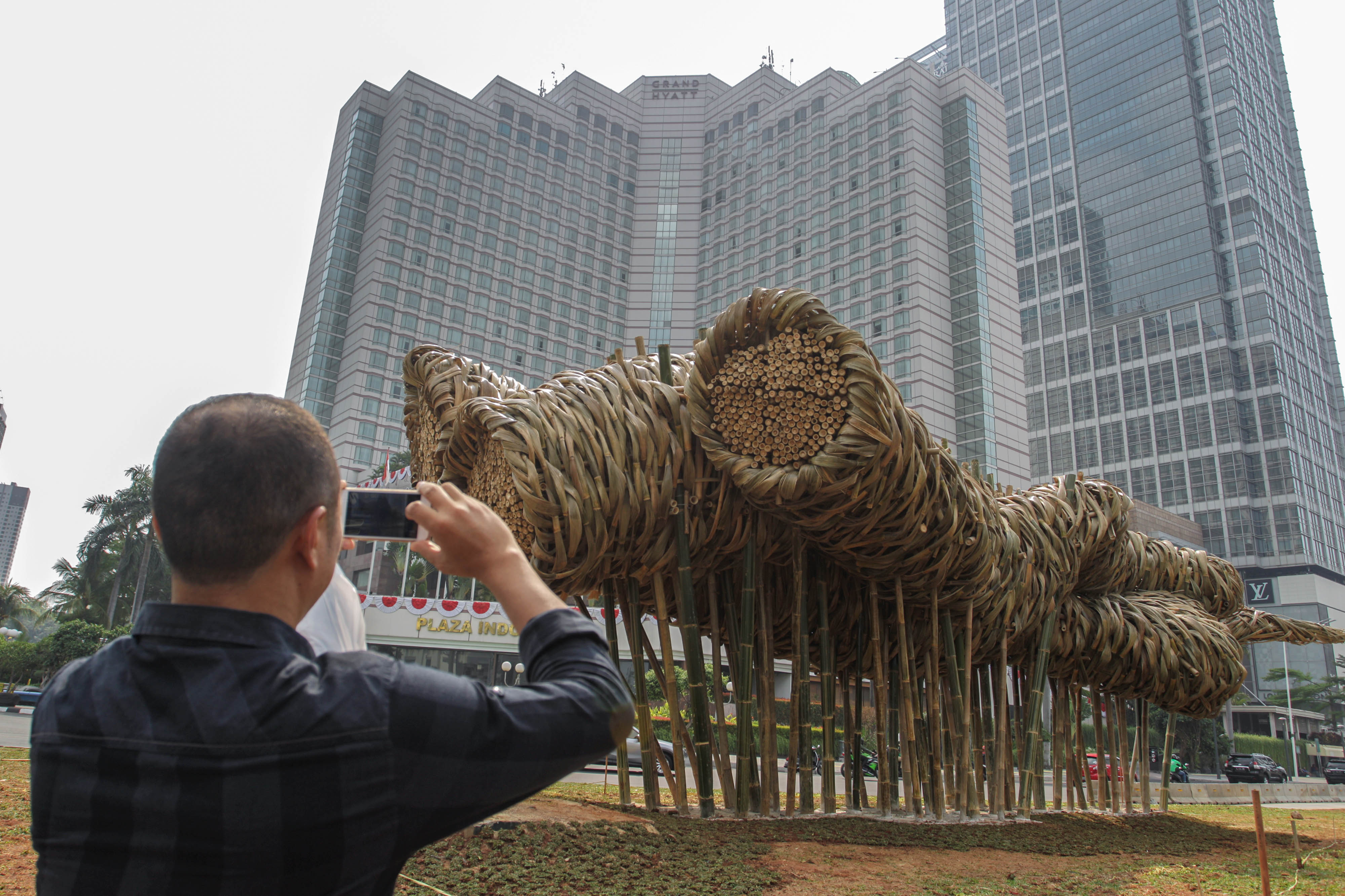 Seorang pejalan kaki mengabadikan karya seni instalasi berbahan dasar bambu karya seniman bambu Joko Avianto terpajang di bagian utara Bunda