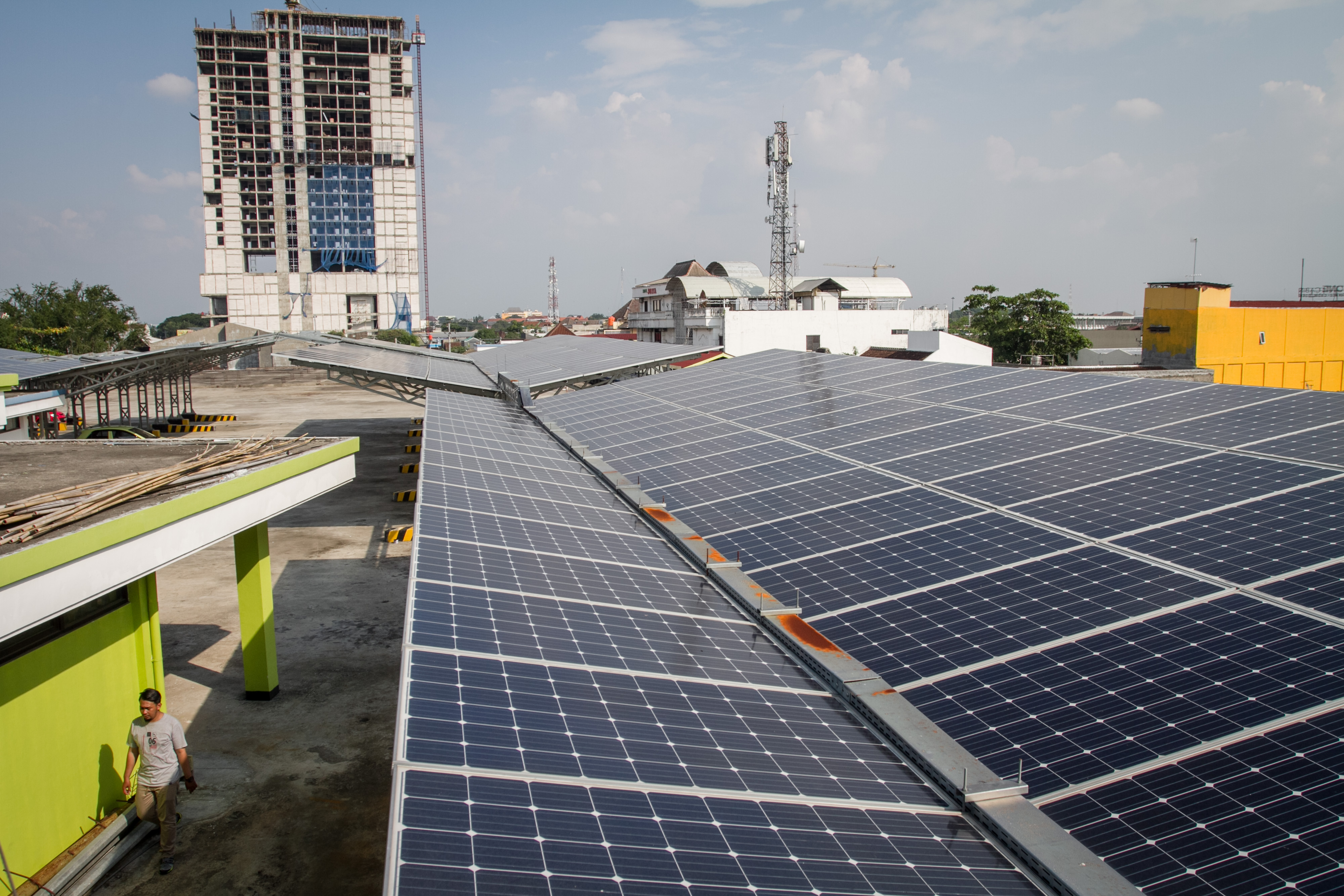 Seorang warga melintas di bawah panel surya Terminal Tirtonadi, Solo, Jawa Tengah, Rabu (9/1/2019).