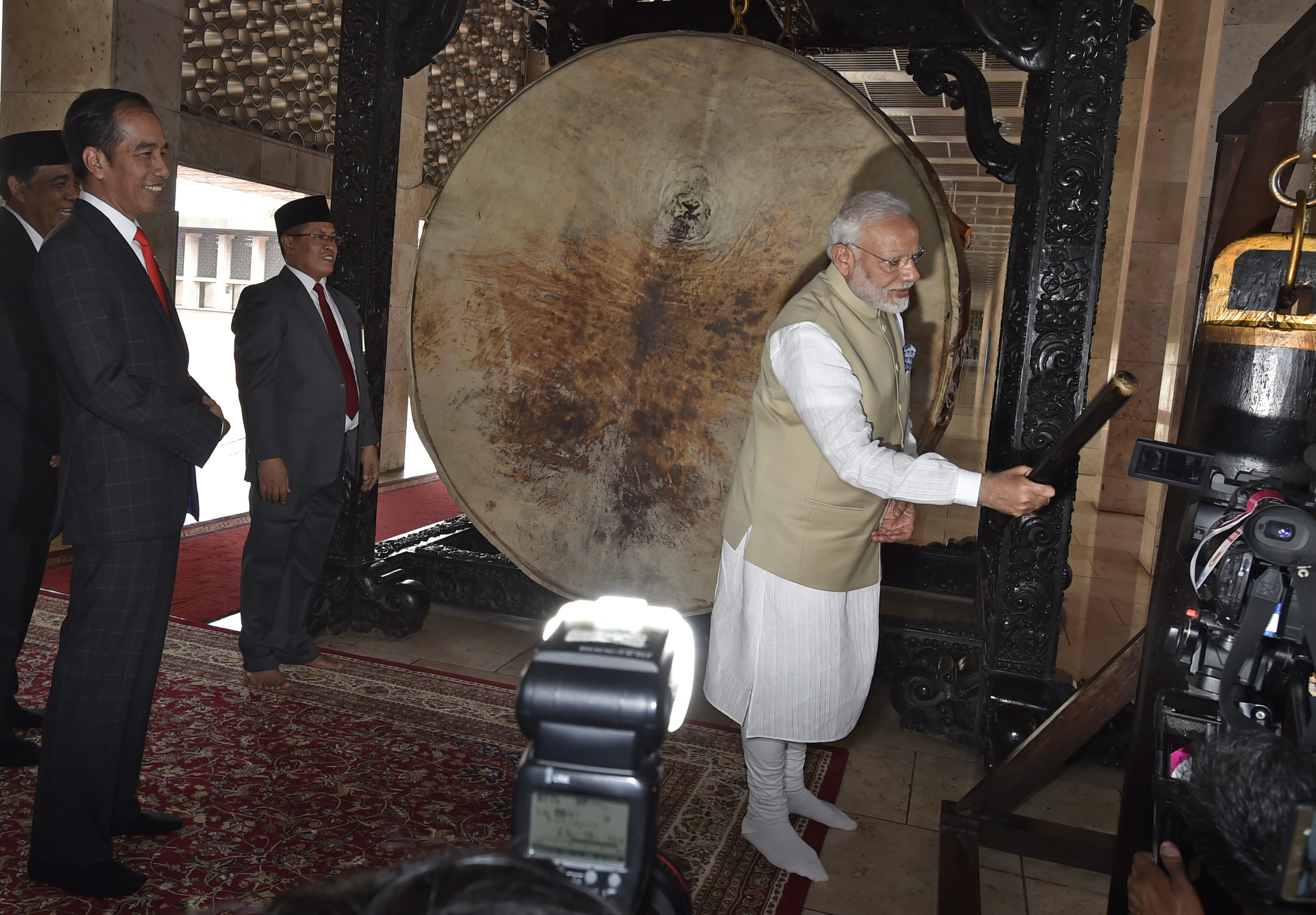 PM India Narendra Modi (kanan) mencoba memukul bedug disaksikan Presiden Joko Widodo (kiri) ketika mengunjungi Masjid Istiqlal.