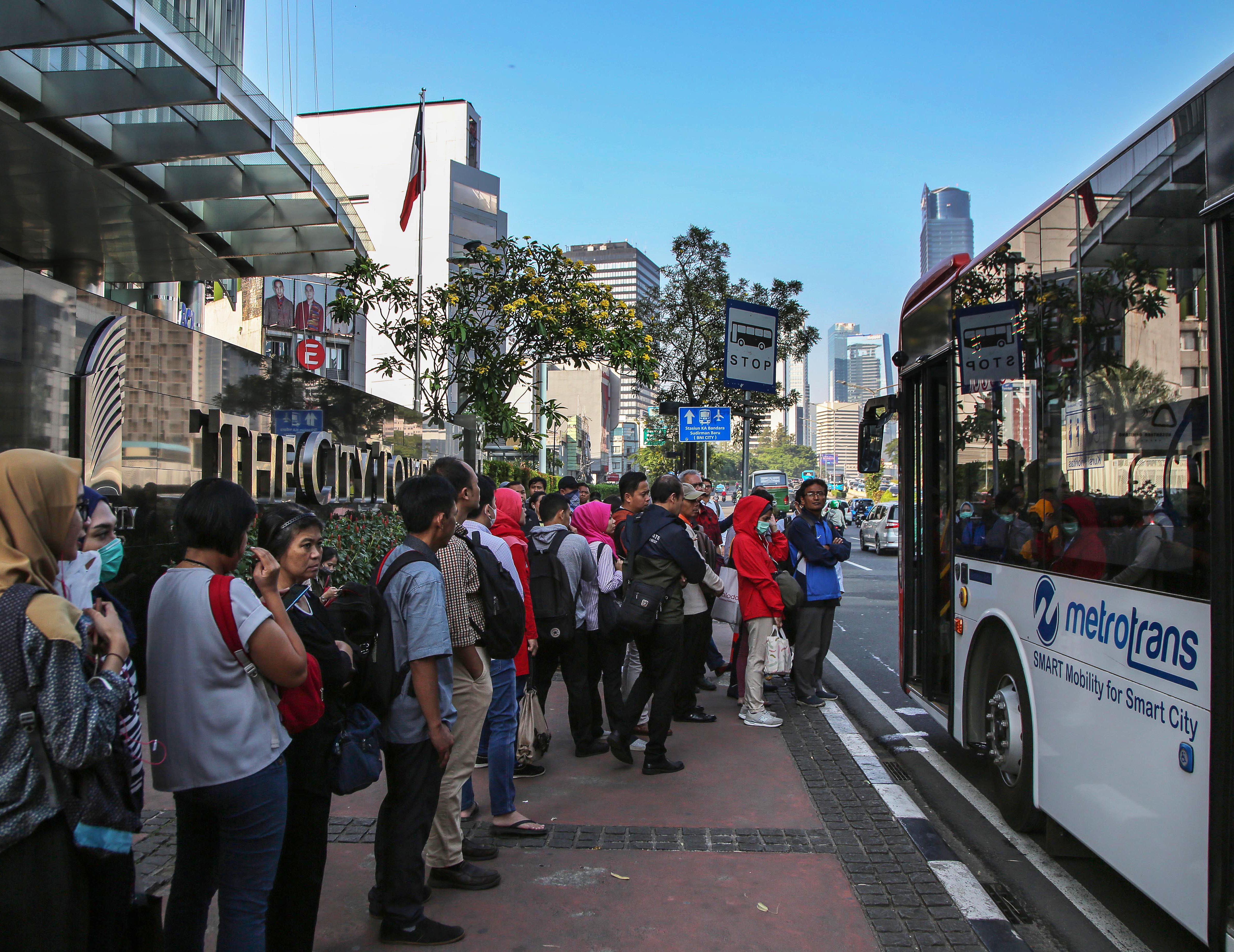  Pekerja antre menaiki bus Metrotrans di kawasan Sudirman, Jakarta, Selasa (18/6). 