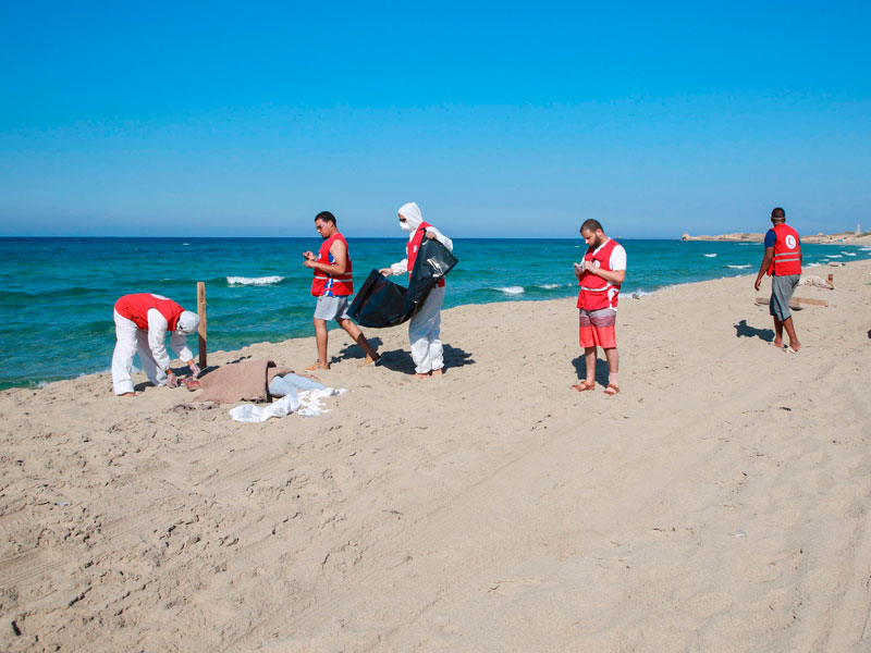 Petugas di lepas pantai Libia menutupi tubuh korban migran yang tenggelam setelah kapal yang mereka tumpagi tenggelam.
