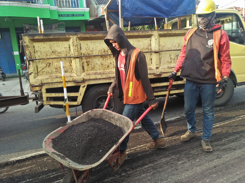 Sejumlah pekerja melakukan proses perbaikan jalan di jalur Pantura, Padaharja, Kabupaten Tegal, Jawa Tengah.