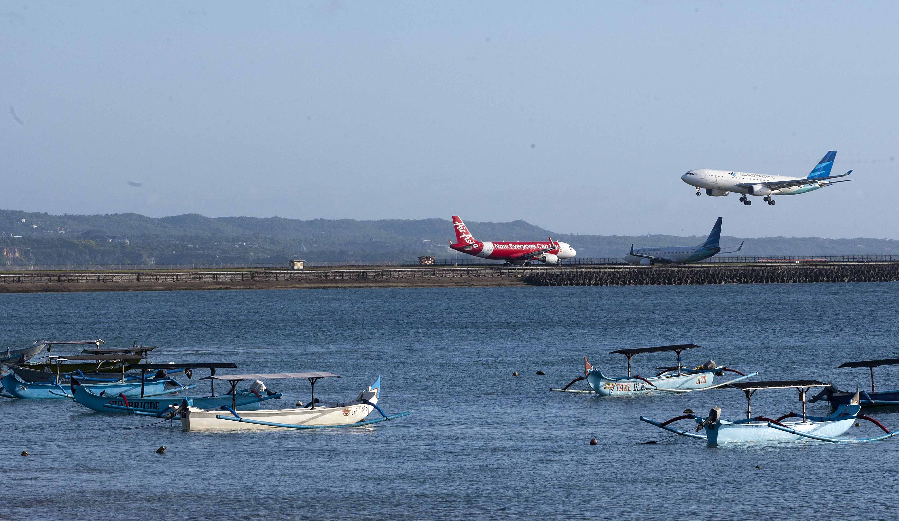 Pesawat Garuda saat akan mendarat, sementara pesawat AirAsia bersiap akan terbang di Bandara Ngurah Rai, Denpasar, Bali