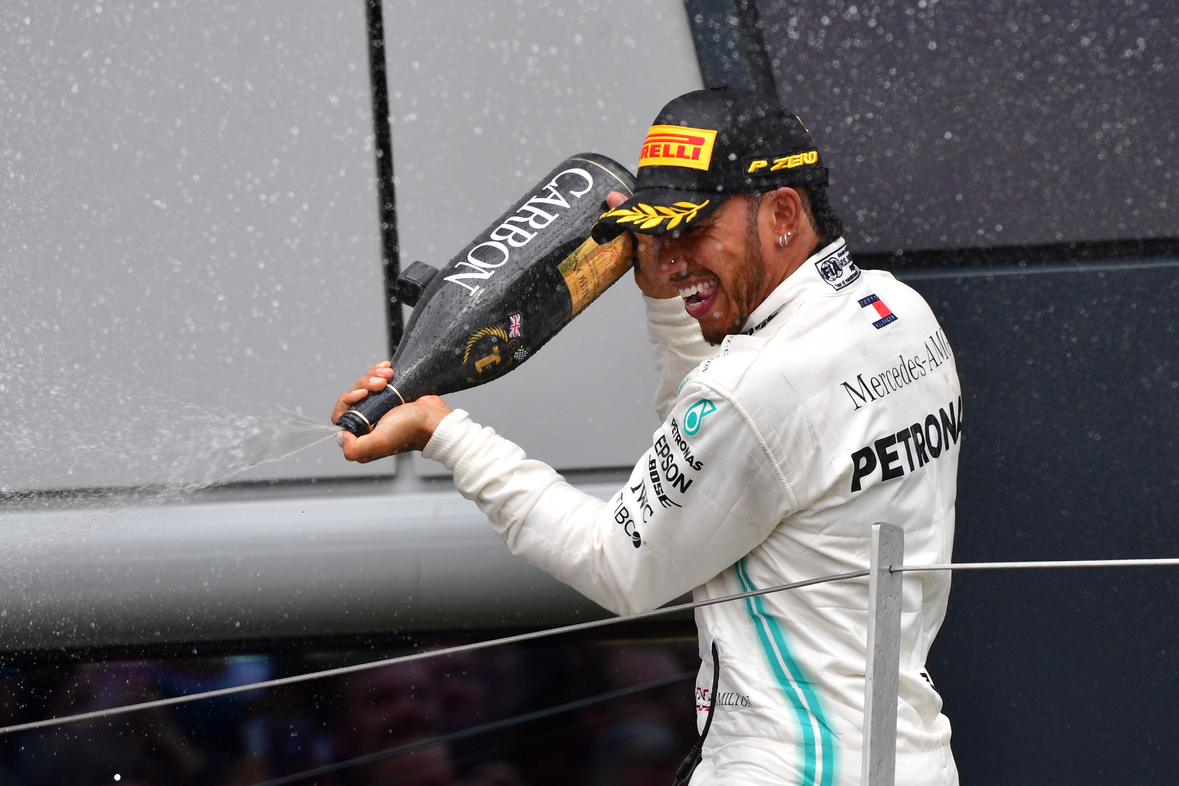 Lewis Hamilton menyemprotkan sampanye di podium saat ia merayakan kemenangan di Grand Prix Formula Satu Inggris  
