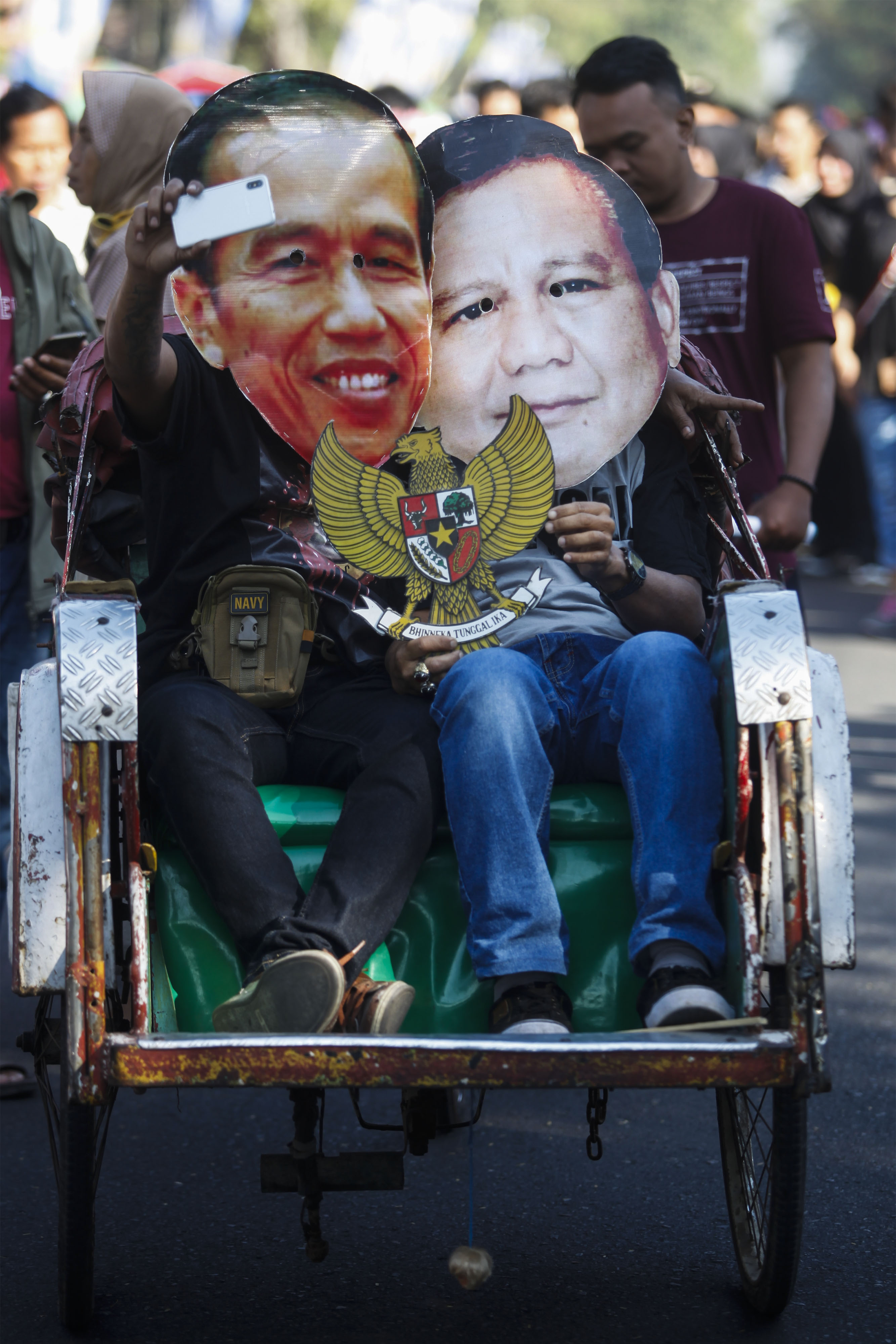 Warga memakai penutup wajah bergambar kontestan Pilpres 2019, Joko Widodo (kiri) dan Prabowo Subianto (kanan) 