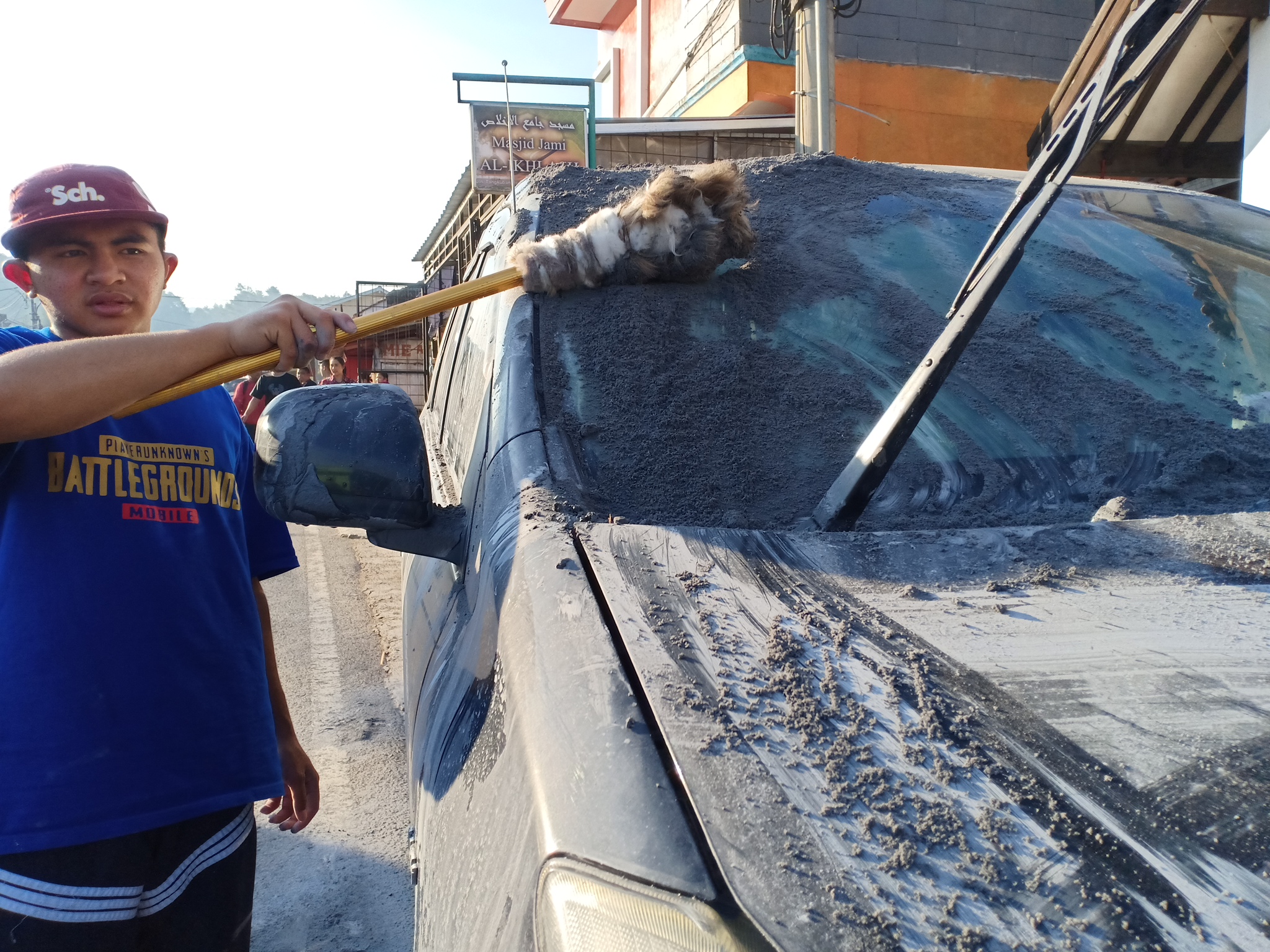Warga membersihkan mobil milik pengunjung dari debu vulkanik pasca erupsi Gunung Tangkuban Parahu pada Jumat (26/7) sore.