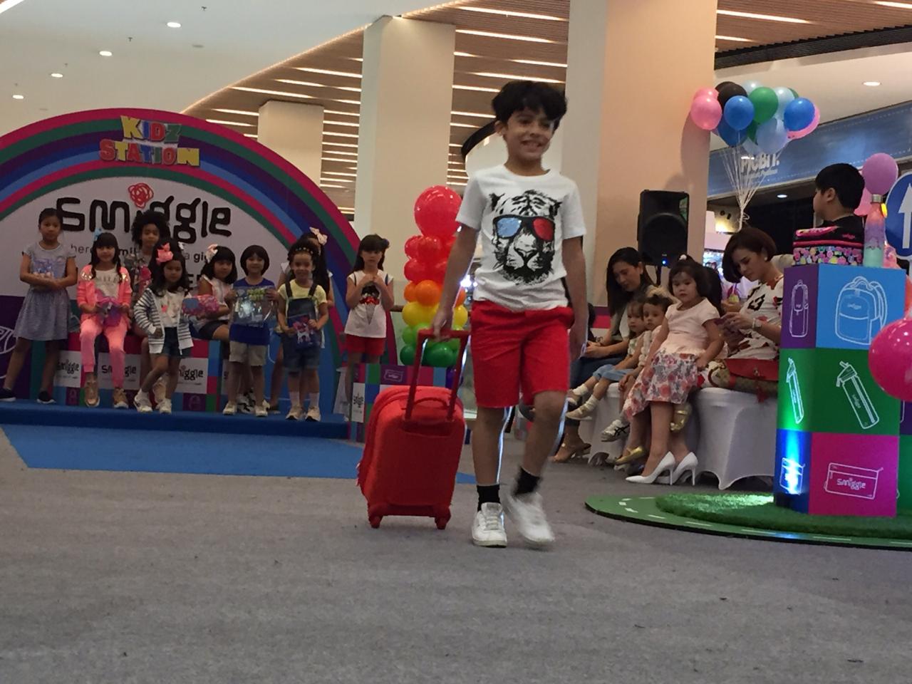 Seorang anak memperagakan dengan membawa perlengkapan sekolah buatan Australia.