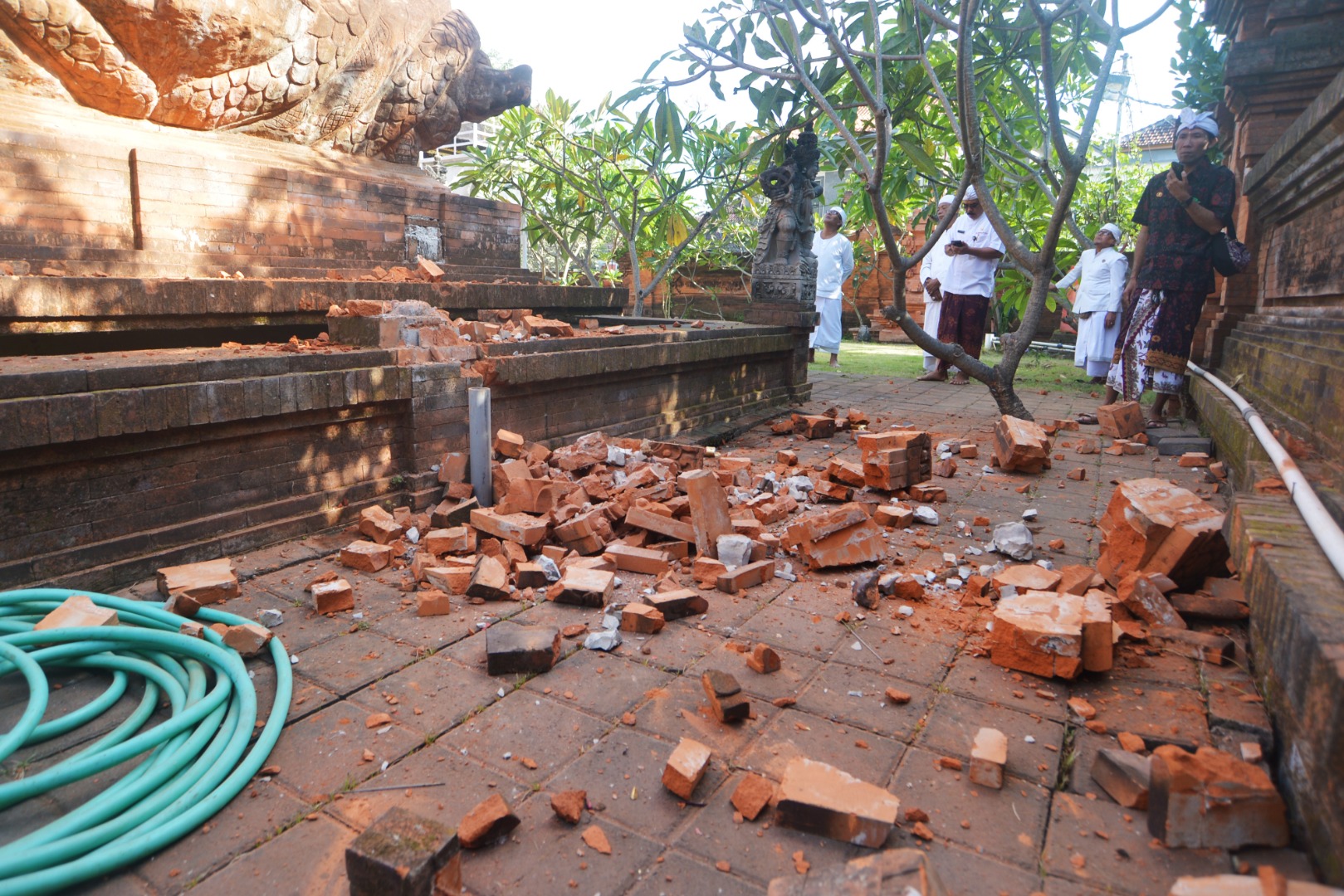 Pemuka agama Hindu memantau kerusakan pada bagian candi yang runtuh akibat gempa di Pura Lokanatha, Denpasar, Bali, Selasa (16/7).